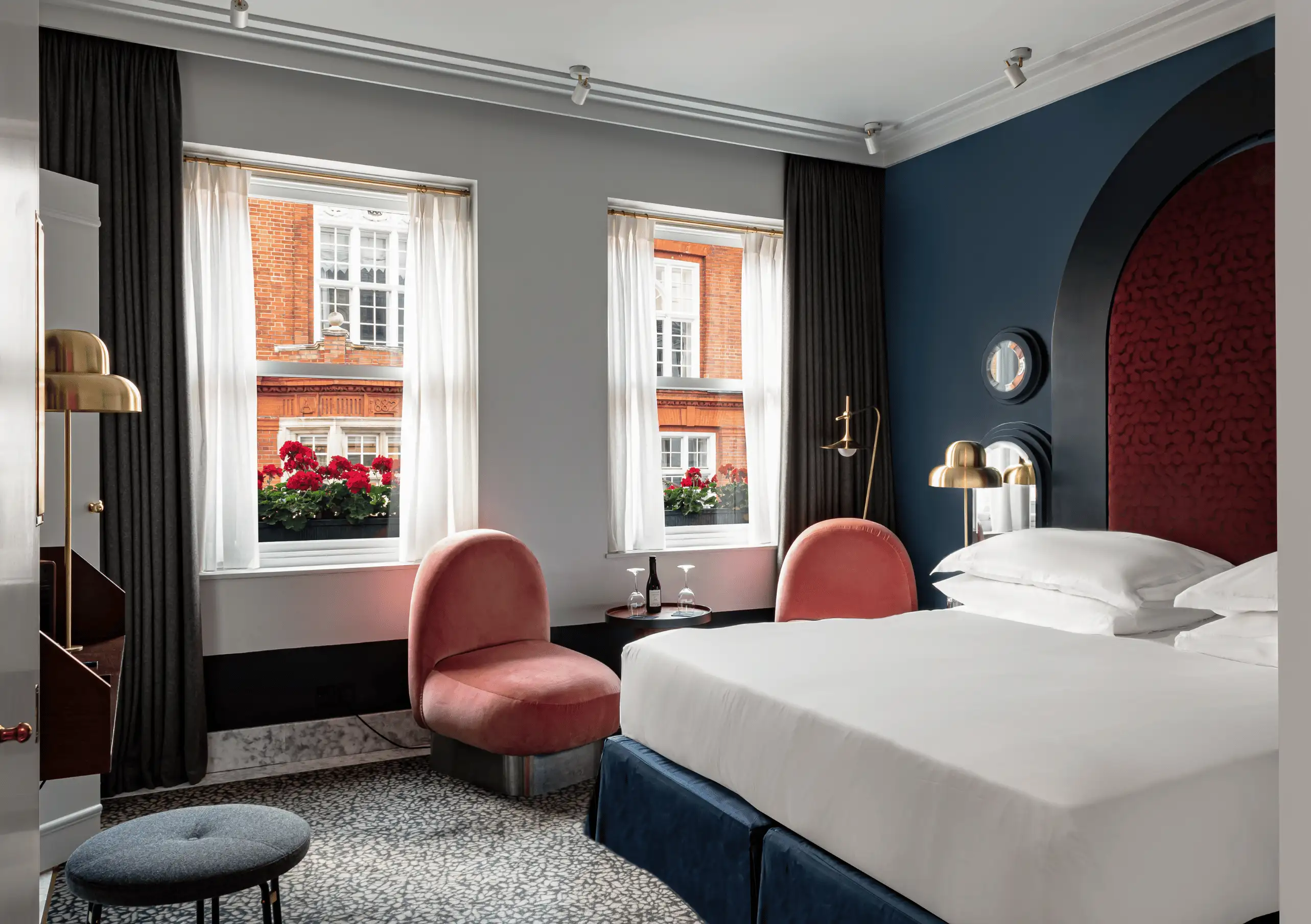 Experimental Group elegantly designed hotel bedroom with navy blue and red accent walls, plush armchairs and large windows in Paris