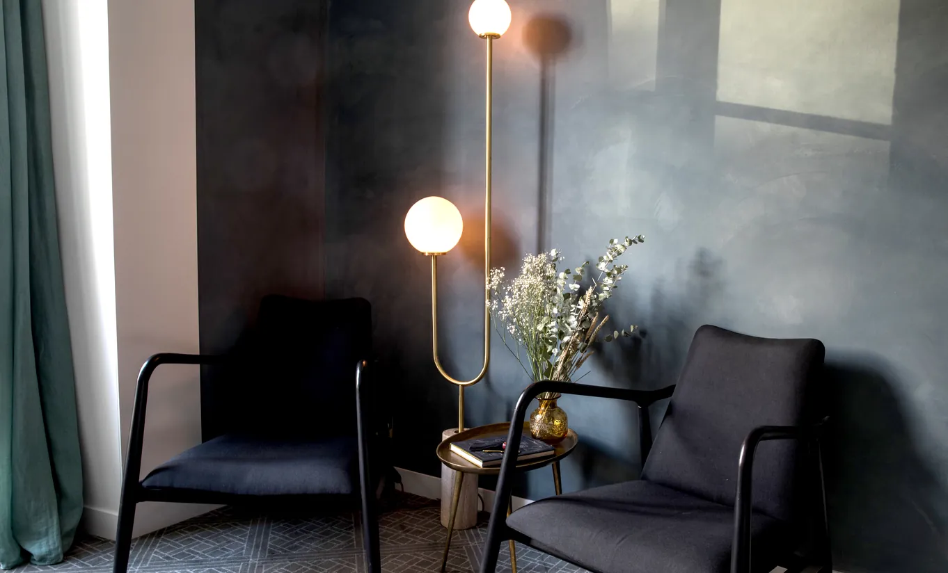 Sitting area with two black armchairs, a gold floor lamp and dark grey walls in the Grand Boulevard room at Grands Boulevards Experimental, luxury boutique hotel on les Grands Boulevards, Paris