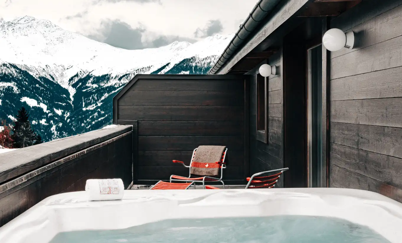 Private outdoor jacuzzi with a panoramic view of the snowy Swiss Alps in the Panorama Suite at Experimental Chalet Verbier, luxury ski and spa hotel in Verbier