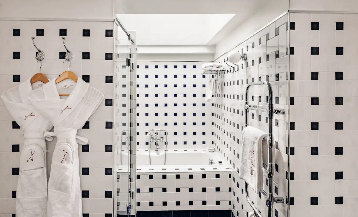 Bathroom with geometric black and white tiled walls and a walk-in shower in the Verbier Suite at Experimental Chalet Verbier