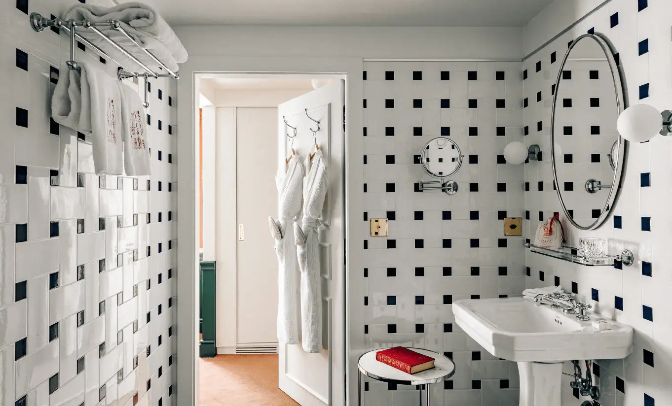 Bathroom with geometric black and white tiled walls and a pedestal sink in the Junior Suite at Experimental Chalet Verbier