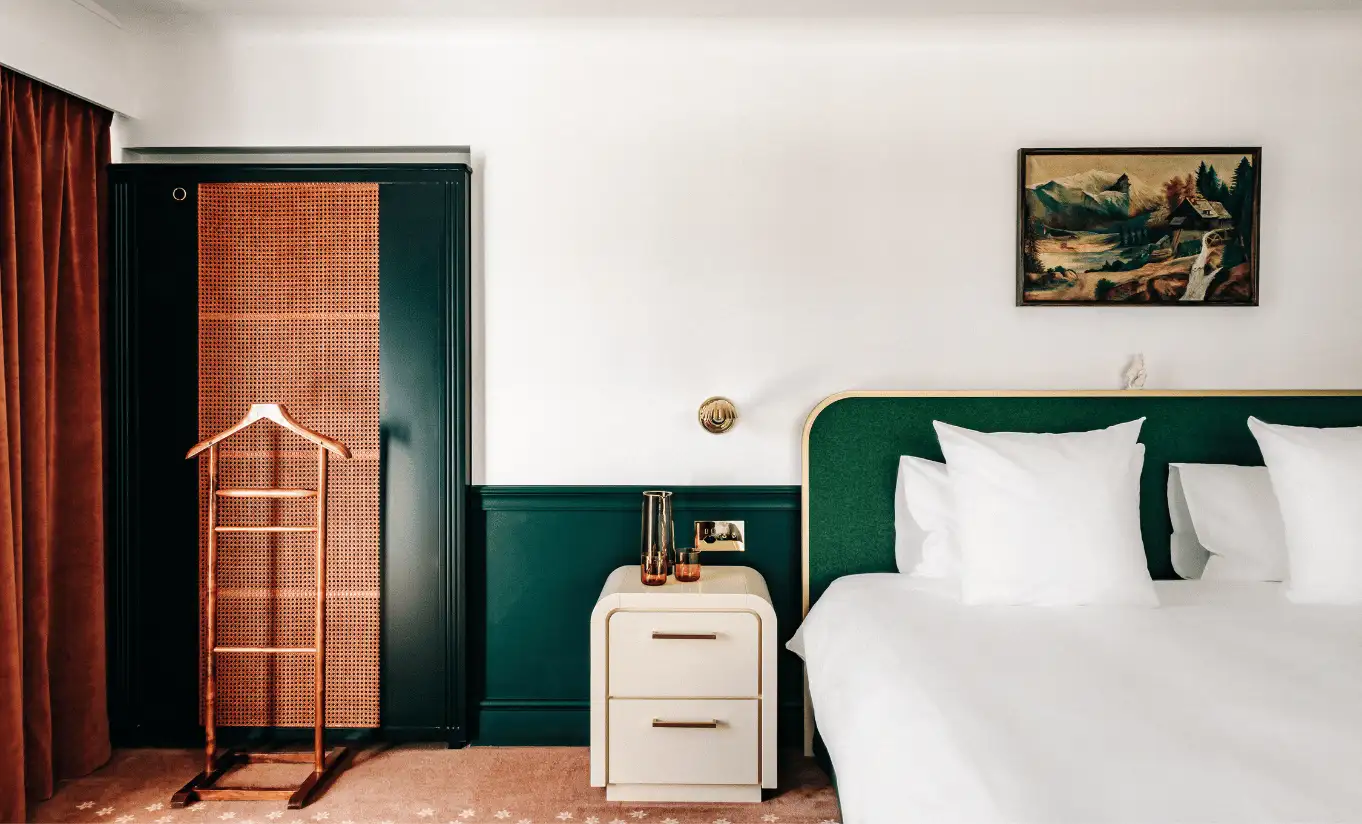 Bedroom with a white double bed, dark green wall panelling and a wooden door in the Deluxe Room Terrace at Experimental Chalet Verbier
