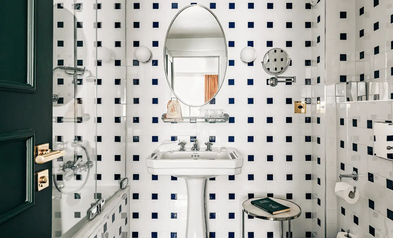 Bathroom with geometric black and white tiled walls and a pedestal sink in the Superior Room Terrace at Experimental Chalet Verbier