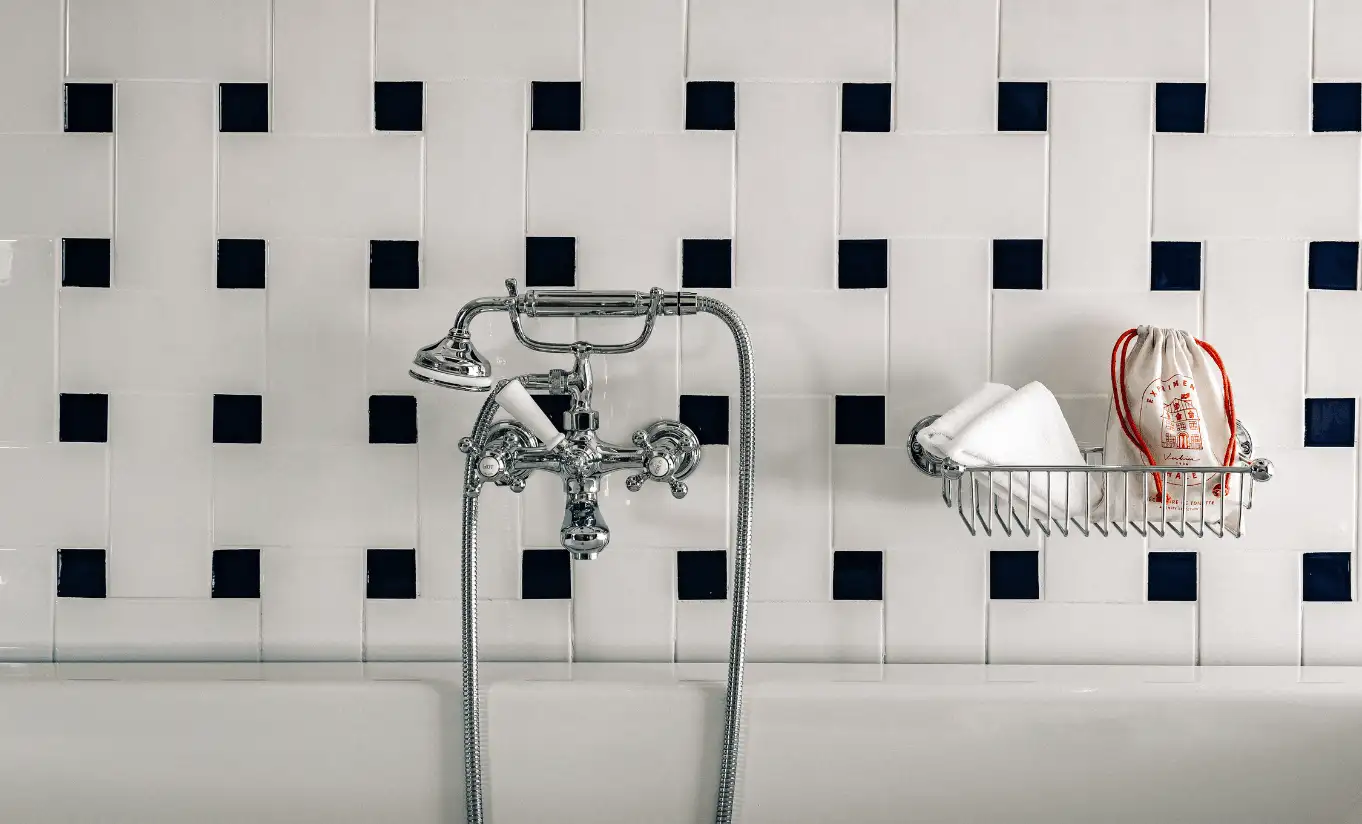 Bathroom with geometric black and white tiled walls and a vintage freestanding shower in the Superior Room at Experimental Chalet Verbier