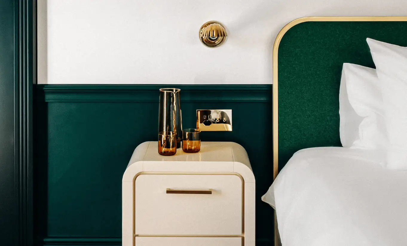 Detail of a bedroom with a cream bedside table and dark green wall panelling in the Superior Room at Experimental Chalet Verbier