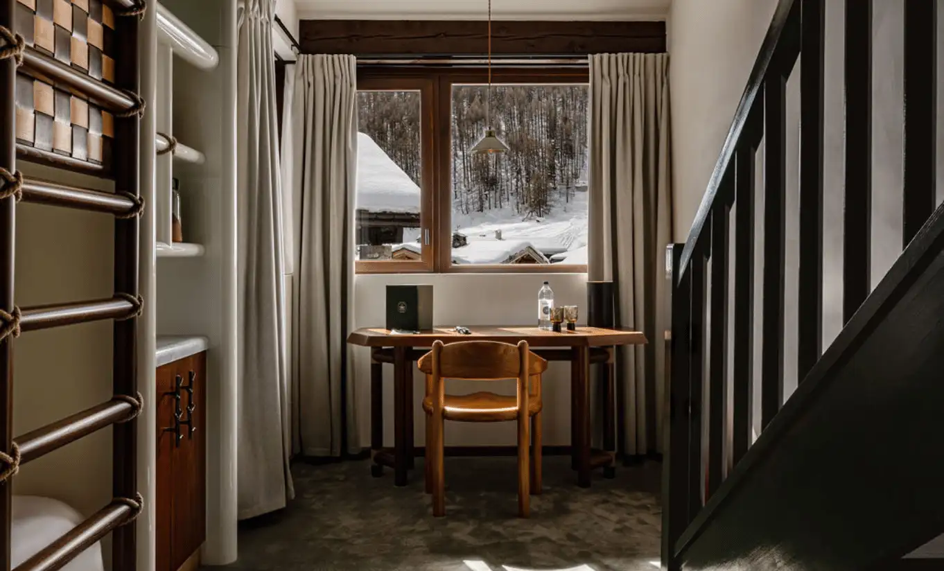 Cosy mezzanine study area with built-in shelving, a wooden desk and a snowy mountain view in the Loft Mezzanine Bunk Beds at Experimental Chalet Val d'Isère