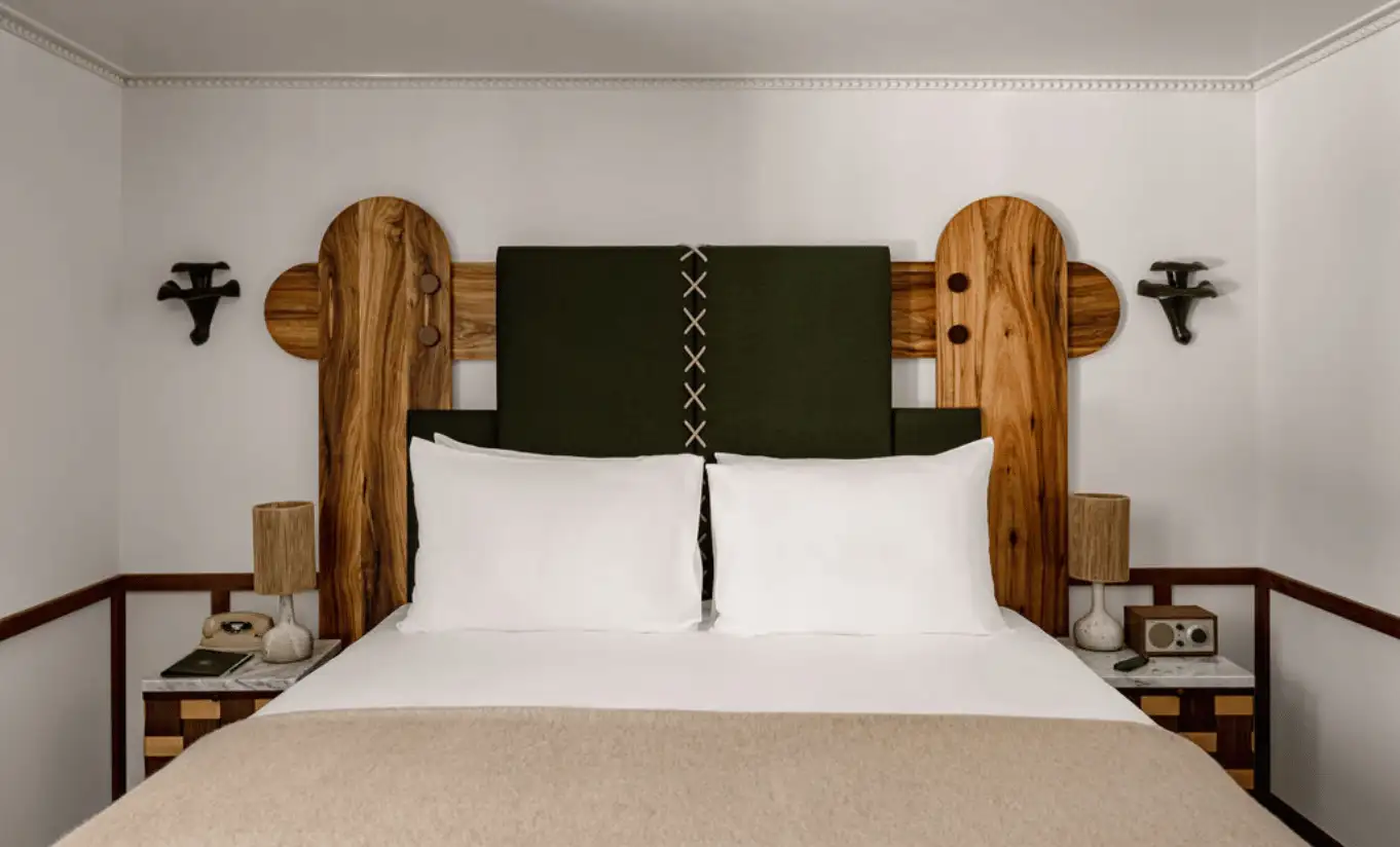 Double bed with a white duvet, wooden headboard and green upholstered panel in the Loft Mezzanine Bunk Beds at Experimental Chalet Val d'Isère