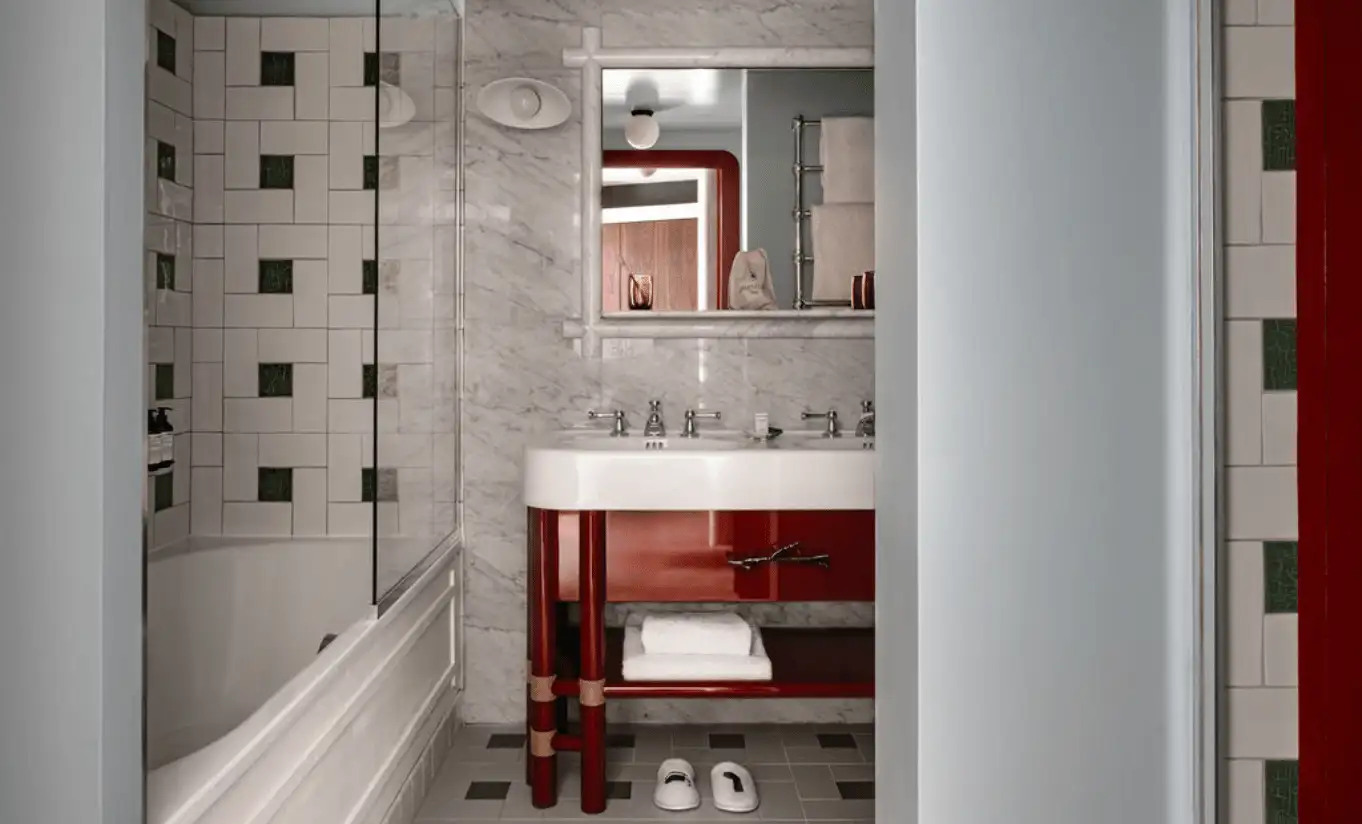 Salle de bain avec carrelage sombre géométrique, meuble vasque rouge et baignoire dans la Junior Suite Solaise de l'Experimental Chalet Val d'Isère