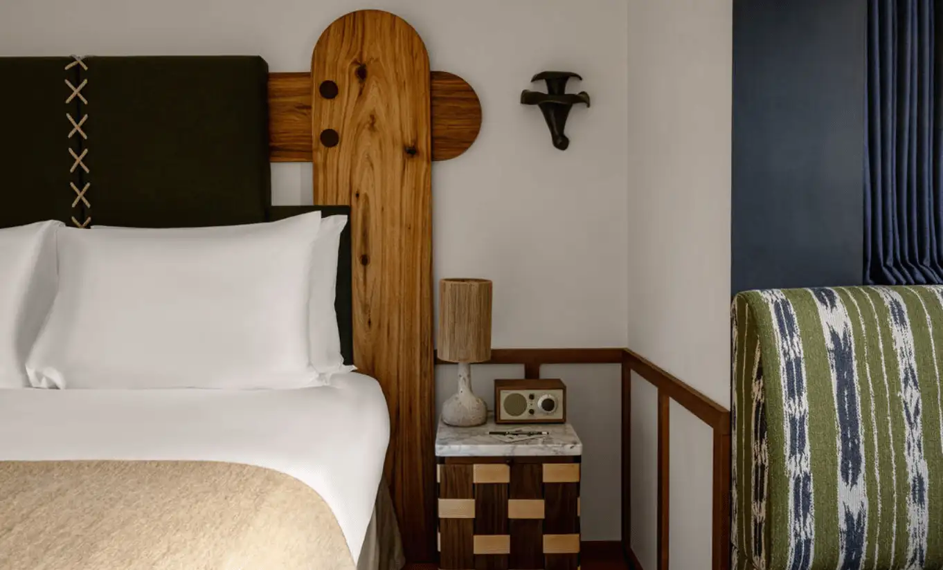 Close-up of a white pillow and wooden headboard with Alpine-style wall sconces in the Olympic Deluxe at Experimental Chalet Val d'Isère