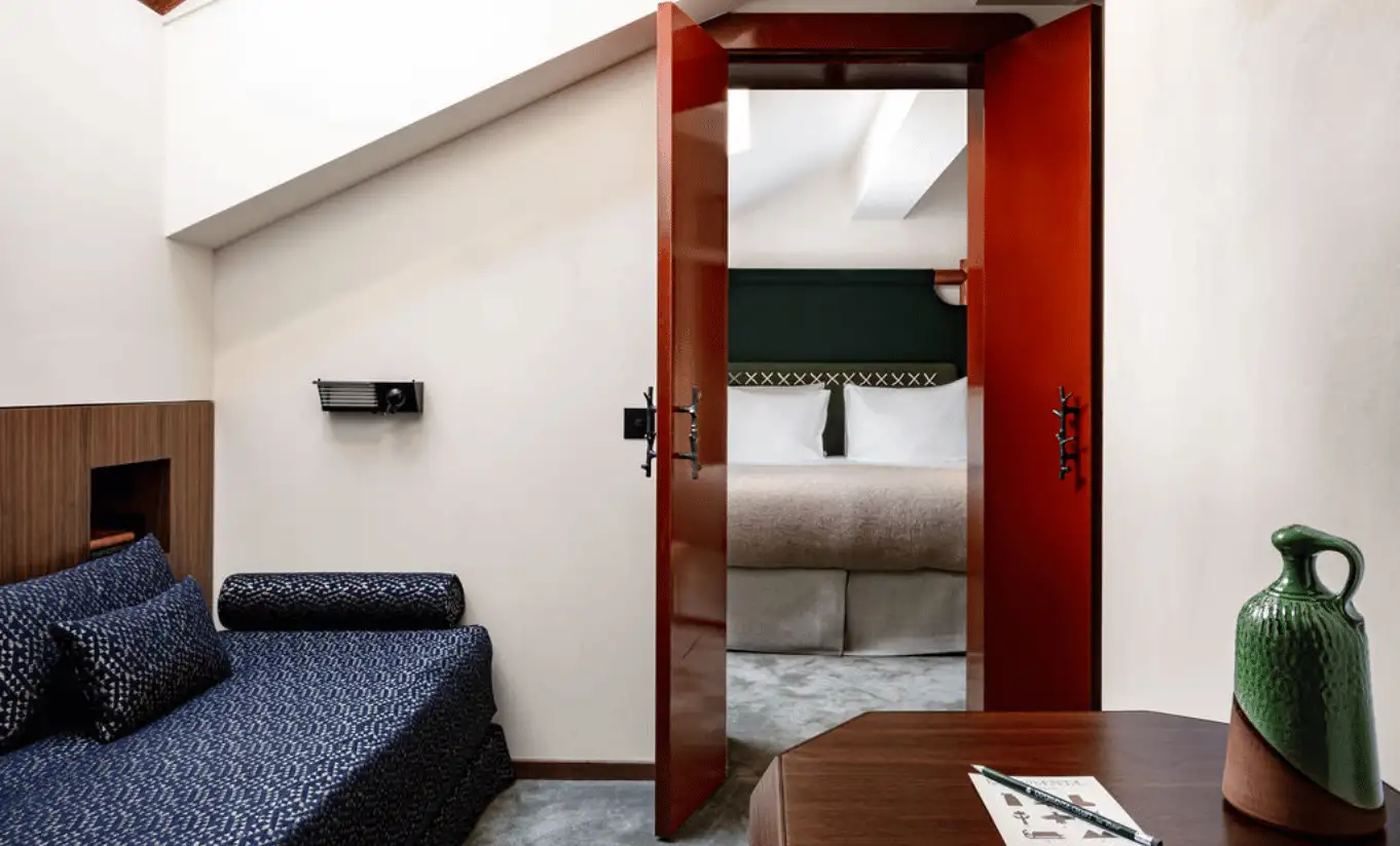 Compact sitting area with a navy blue sofa and red door in the Val d'Isère Under the Eaves at Experimental Chalet Val d'Isère