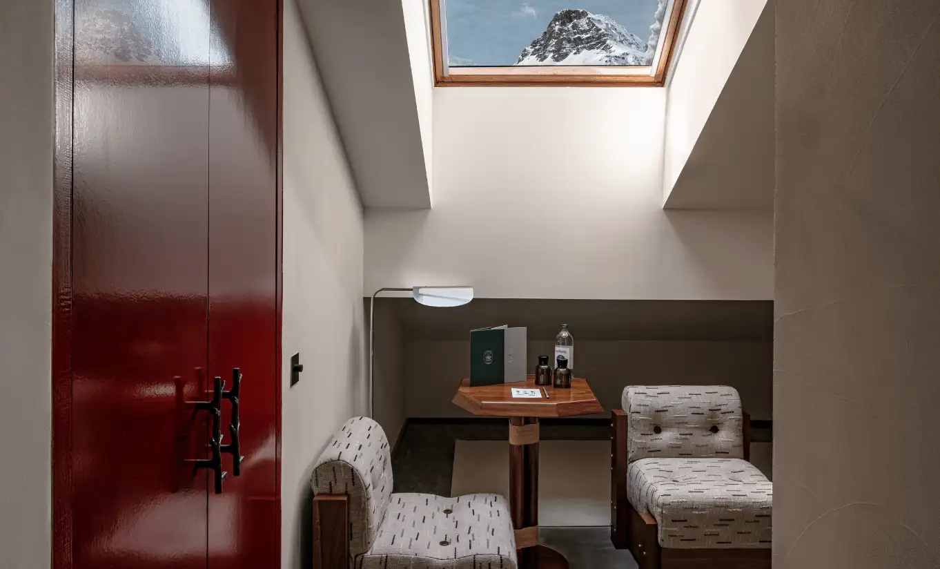 Attic corner with a red door, wooden side table and a skylight in the Val d'Isère Under the Eaves at Experimental Chalet Val d'Isère