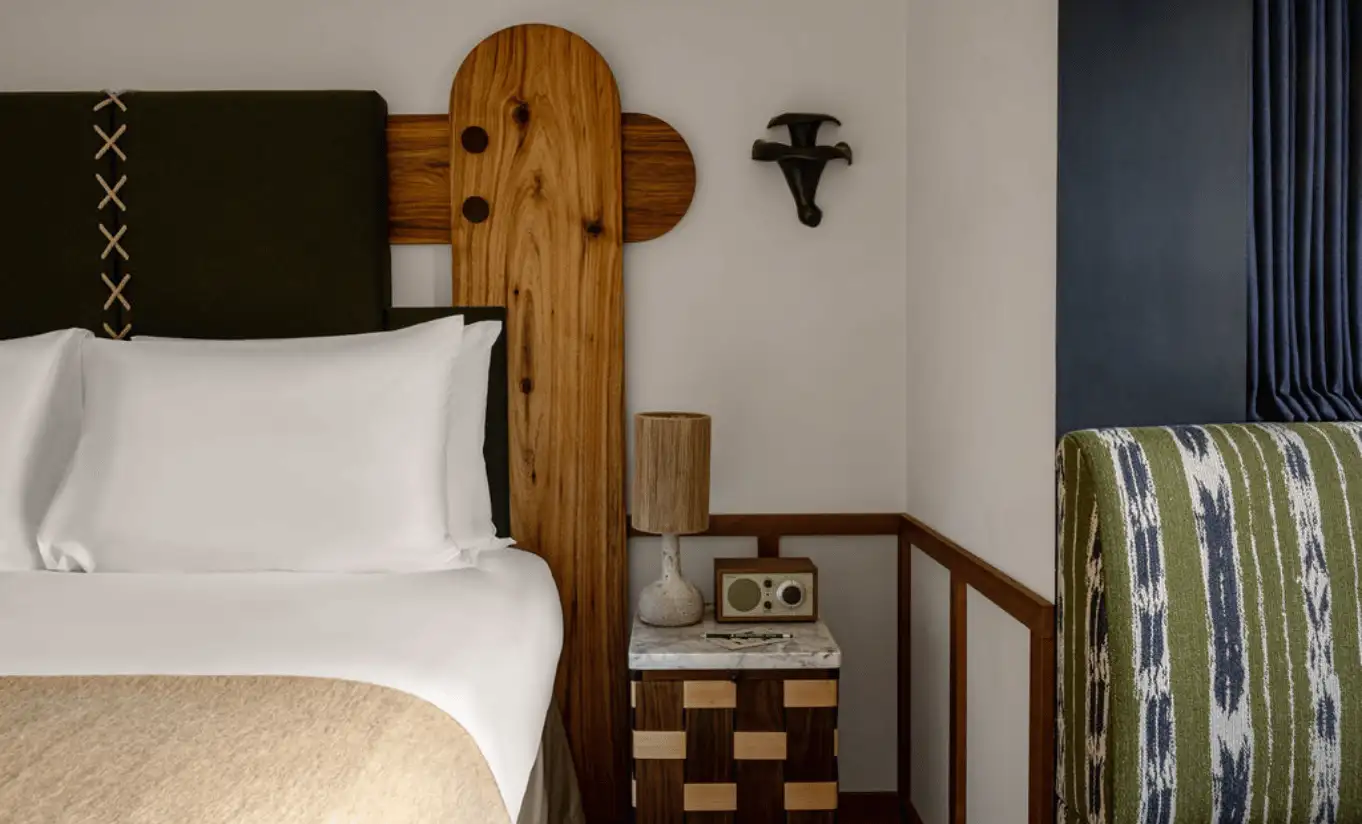 Close-up of a white pillow against a wooden Alpine headboard with green upholstered details in the Val d'Isère Mountain View at Experimental Chalet Val d'Isère