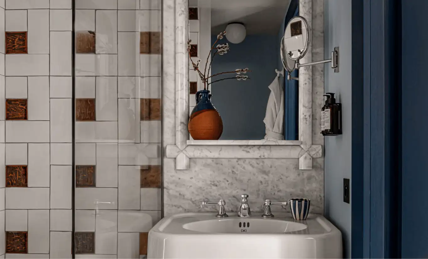 Bathroom with brown and white geometric tiled walls and a pedestal sink in the Val d'Isère Mountain View at Experimental Chalet Val d'Isère