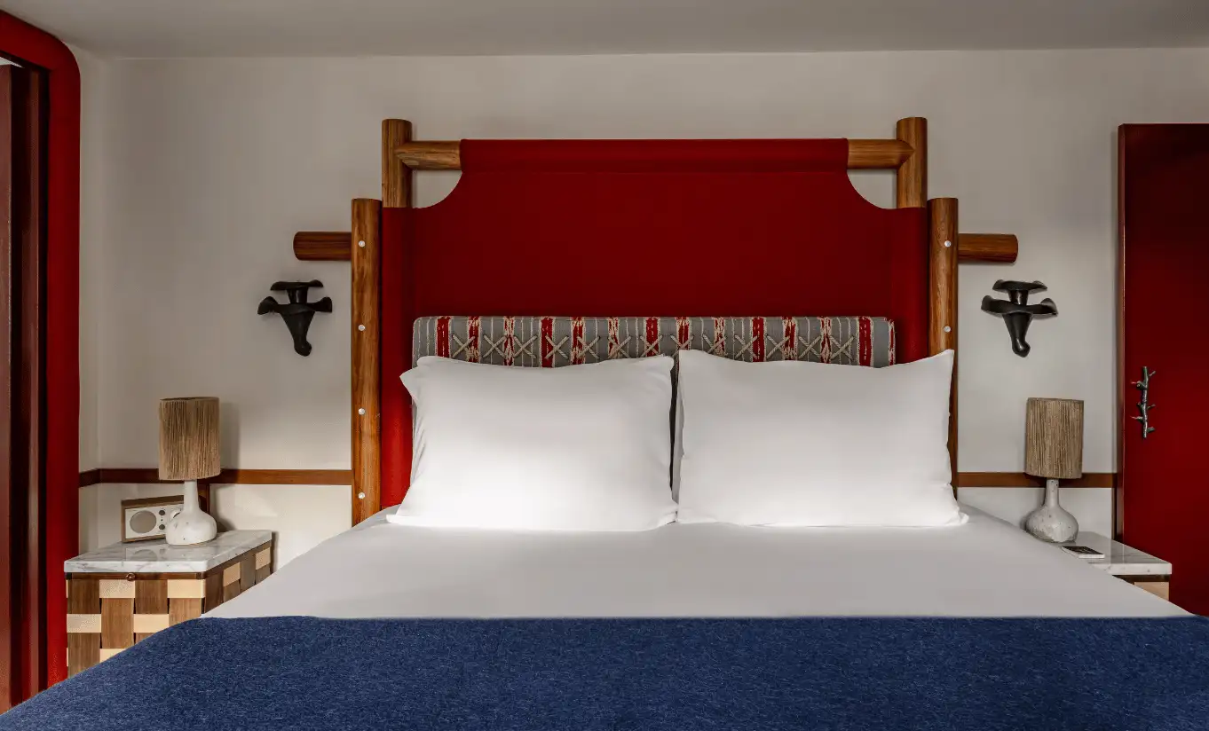 Bedroom with a white double bed, red headboard and wooden bedside tables in the Bellevarde Suite at Experimental Chalet Val d'Isère, luxury spa hotel in the French Alps