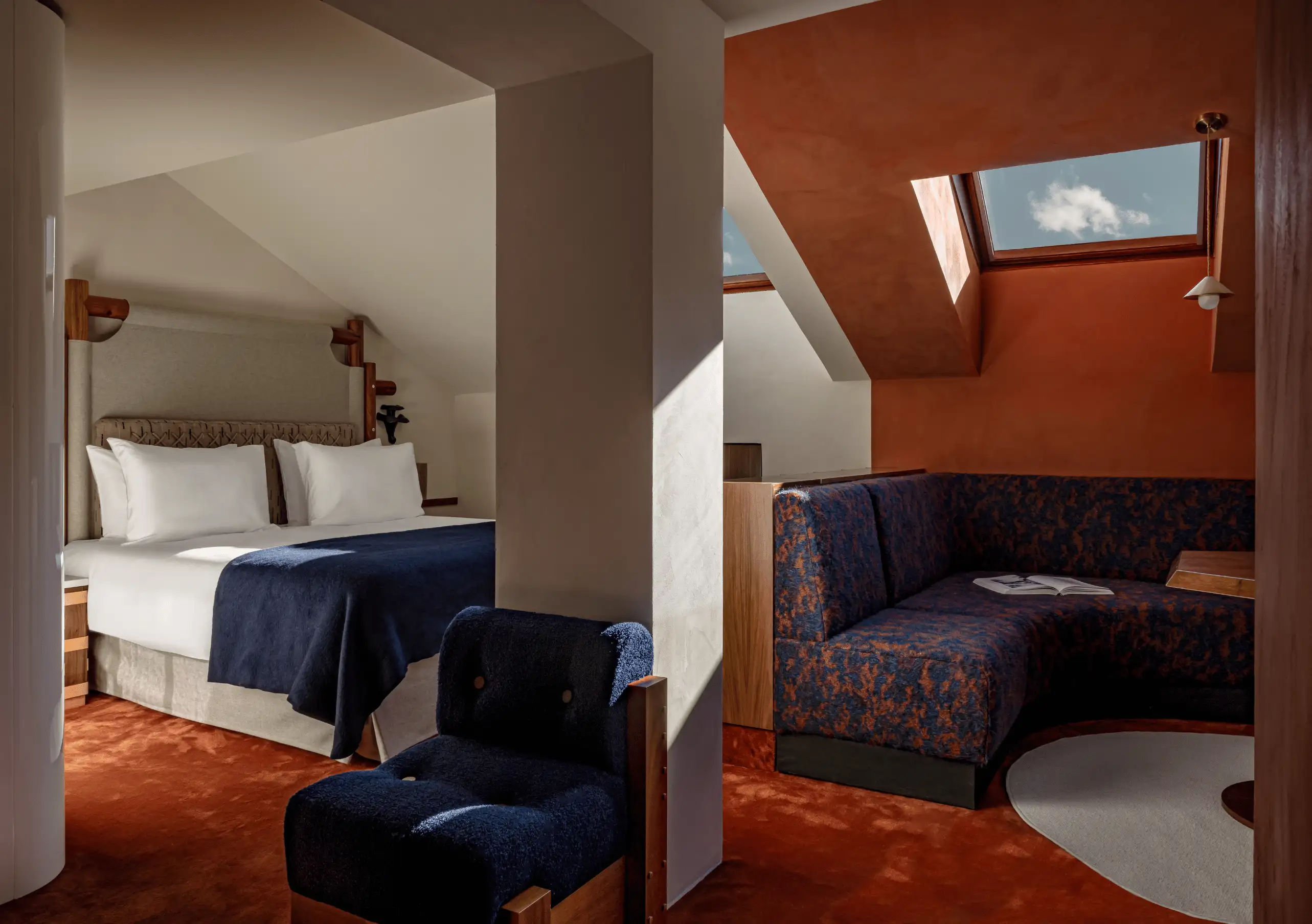 Attic bedroom with terracotta walls, a blue sofa and a skylight in the Solaise Suite at Experimental Chalet Val d'Isère, luxury ski hotel in the French Alps