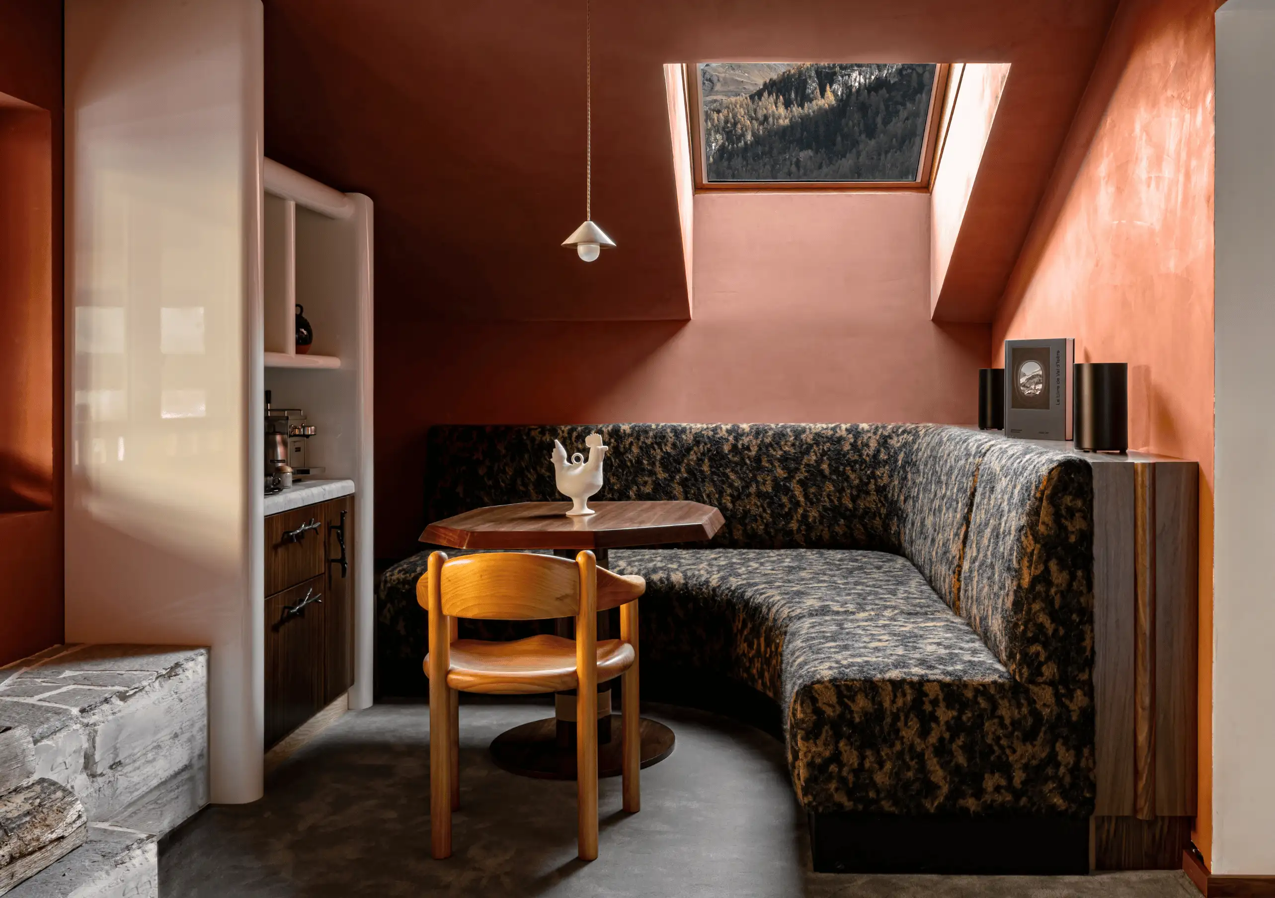 Attic sitting area with terracotta walls, a patterned sofa and wooden furniture in the Iseran Suite at Experimental Chalet Val d'Isère