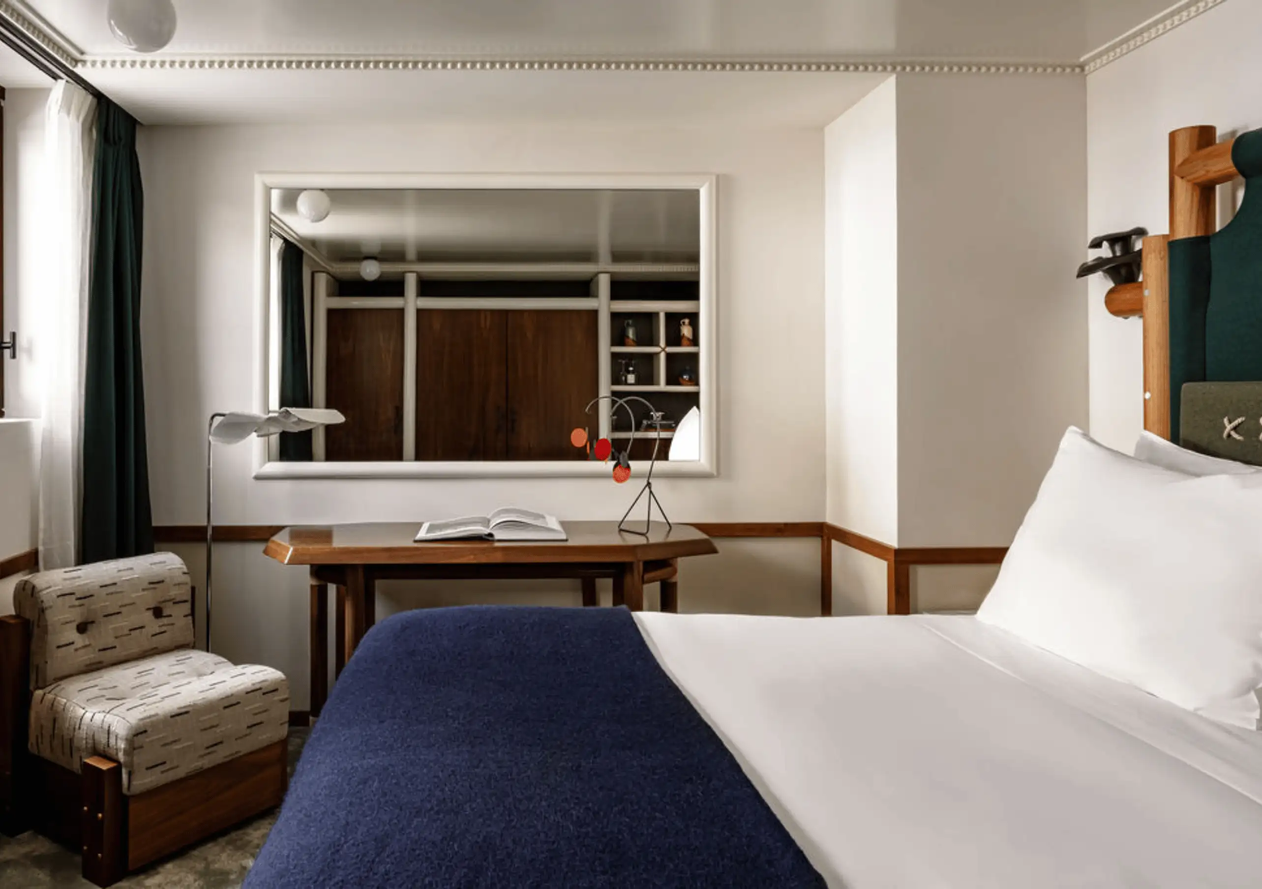 Bedroom with a white double bed, armchair and large mirror in the Glacier Suite with Balcony at Experimental Chalet Val d'Isère
