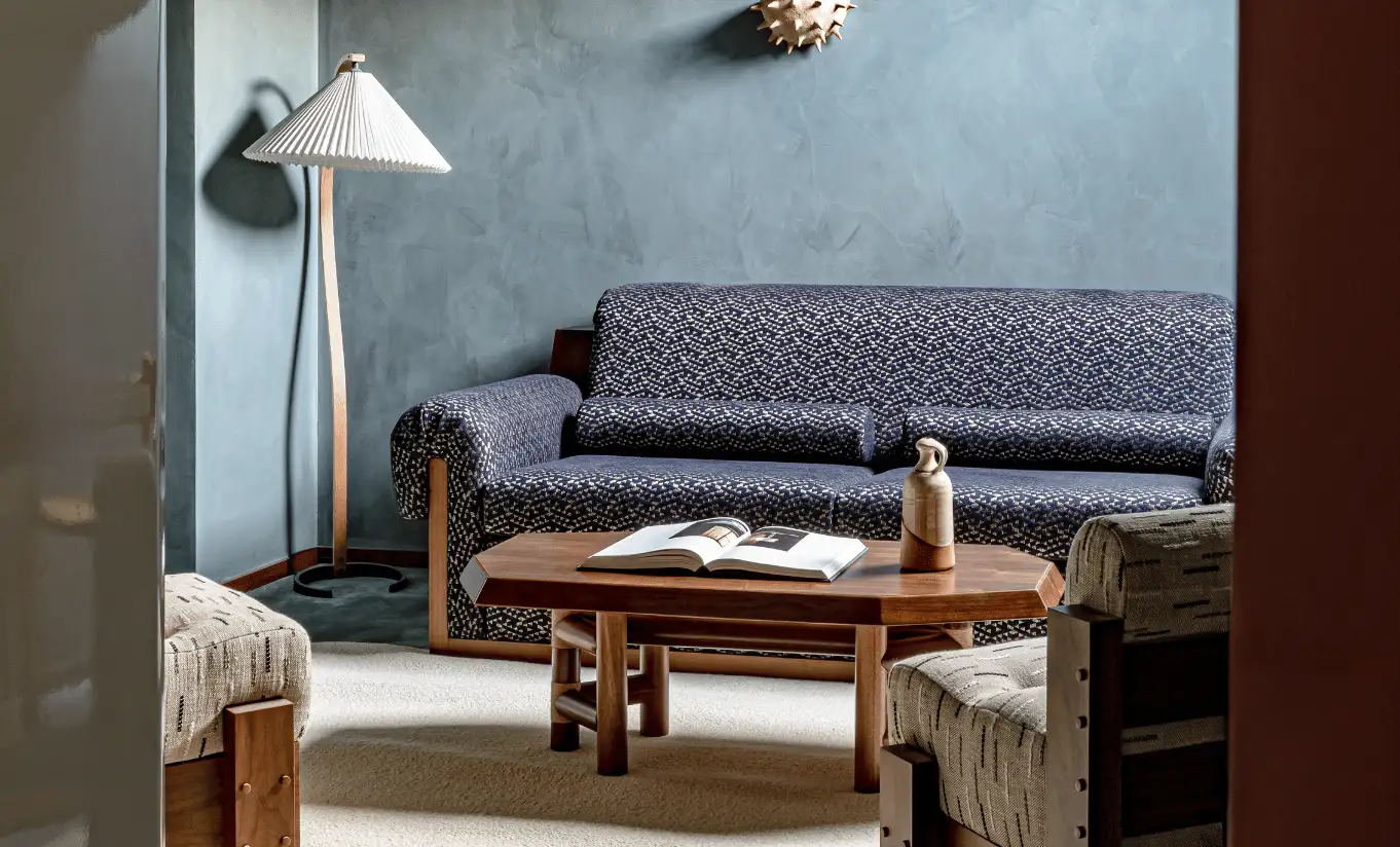 Cosy living area with a blue sofa and wooden coffee table in the Bellevarde Suite at Experimental Chalet Val d'Isère, luxury ski hotel in the French Alps