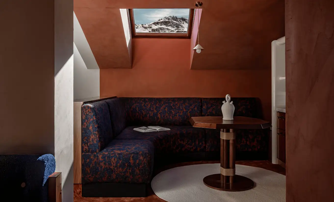Intimate sitting area with terracotta walls, a velvet armchair and candlelight in the Solaise Suite at Experimental Chalet Val d'Isère