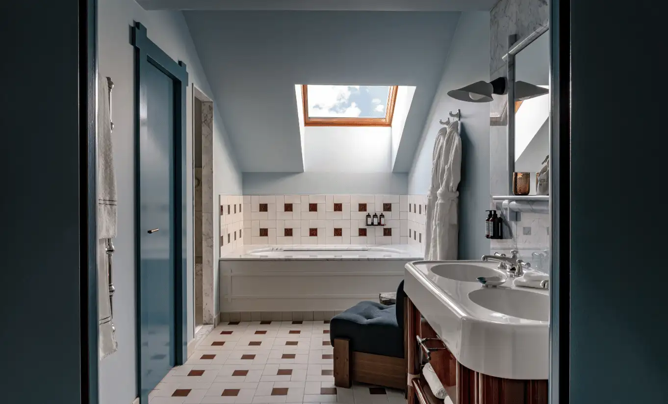 Bathroom with geometric tiled walls, a freestanding bathtub and a skylight in the Solaise Suite at Experimental Chalet Val d'Isère