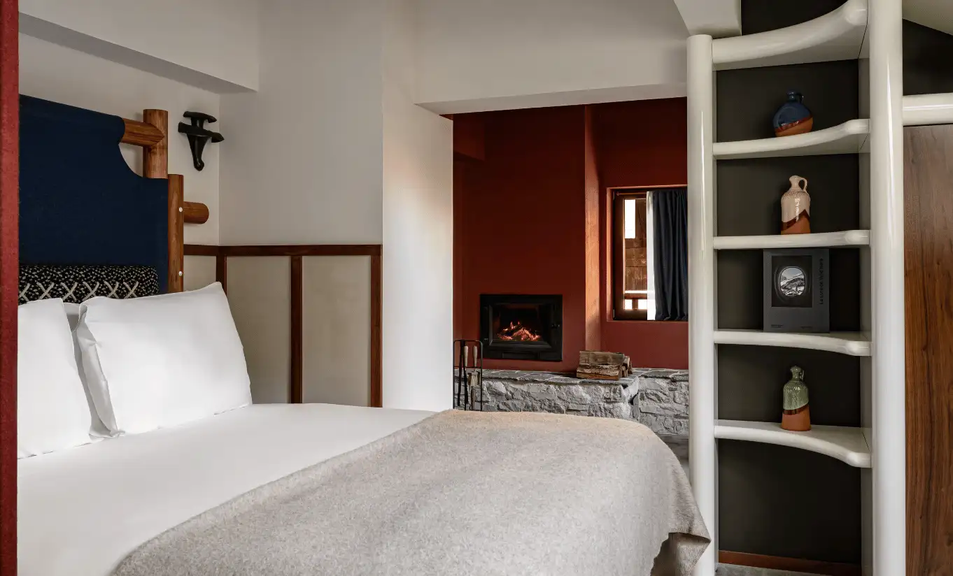 Bedroom corner with a single bed, built-in wooden shelving and red curtains in the Iseran Suite at Experimental Chalet Val d'Isère