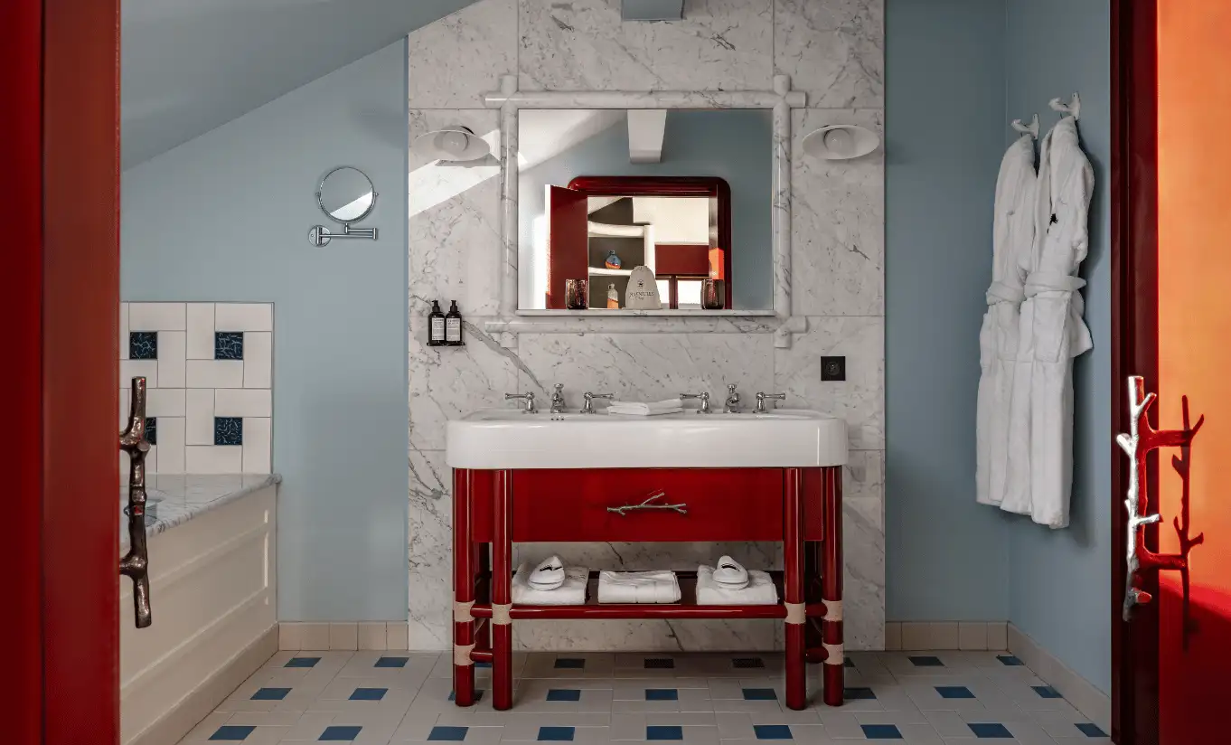 Bathroom corner with geometric tiled floor, a red vanity unit and a wall mirror in the Iseran Suite at Experimental Chalet Val d'Isère