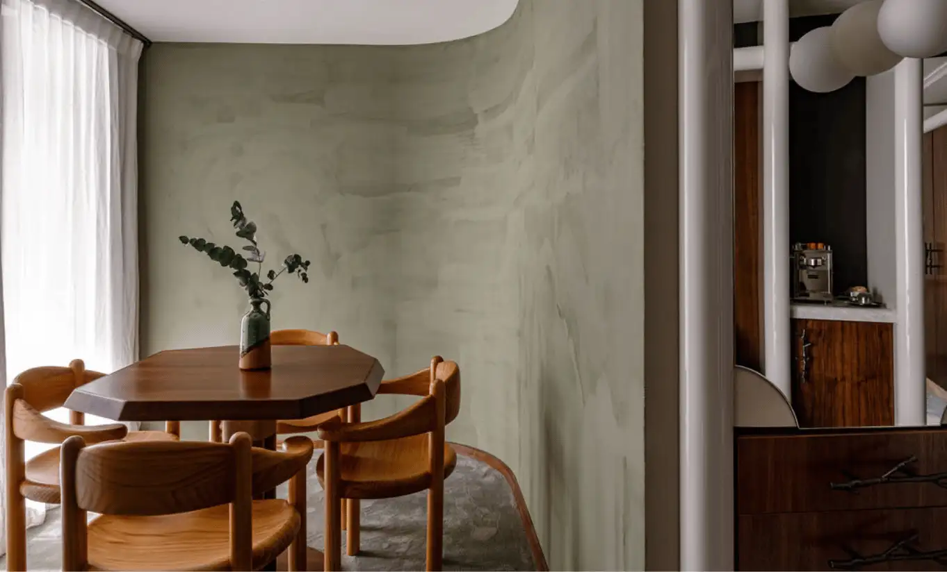Dining area with wooden chairs and a round table in a sage green room in the Glacier Suite with Balcony at Experimental Chalet Val d'Isère