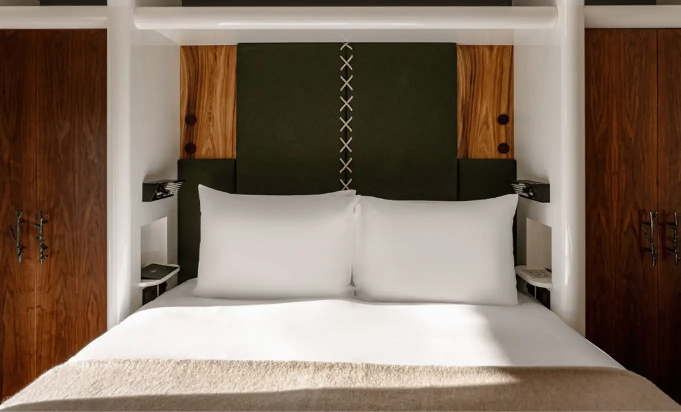 Bedroom with a white double bed, dark green headboard and warm wooden panelling in the Loft at Experimental Chalet Val d'Isère