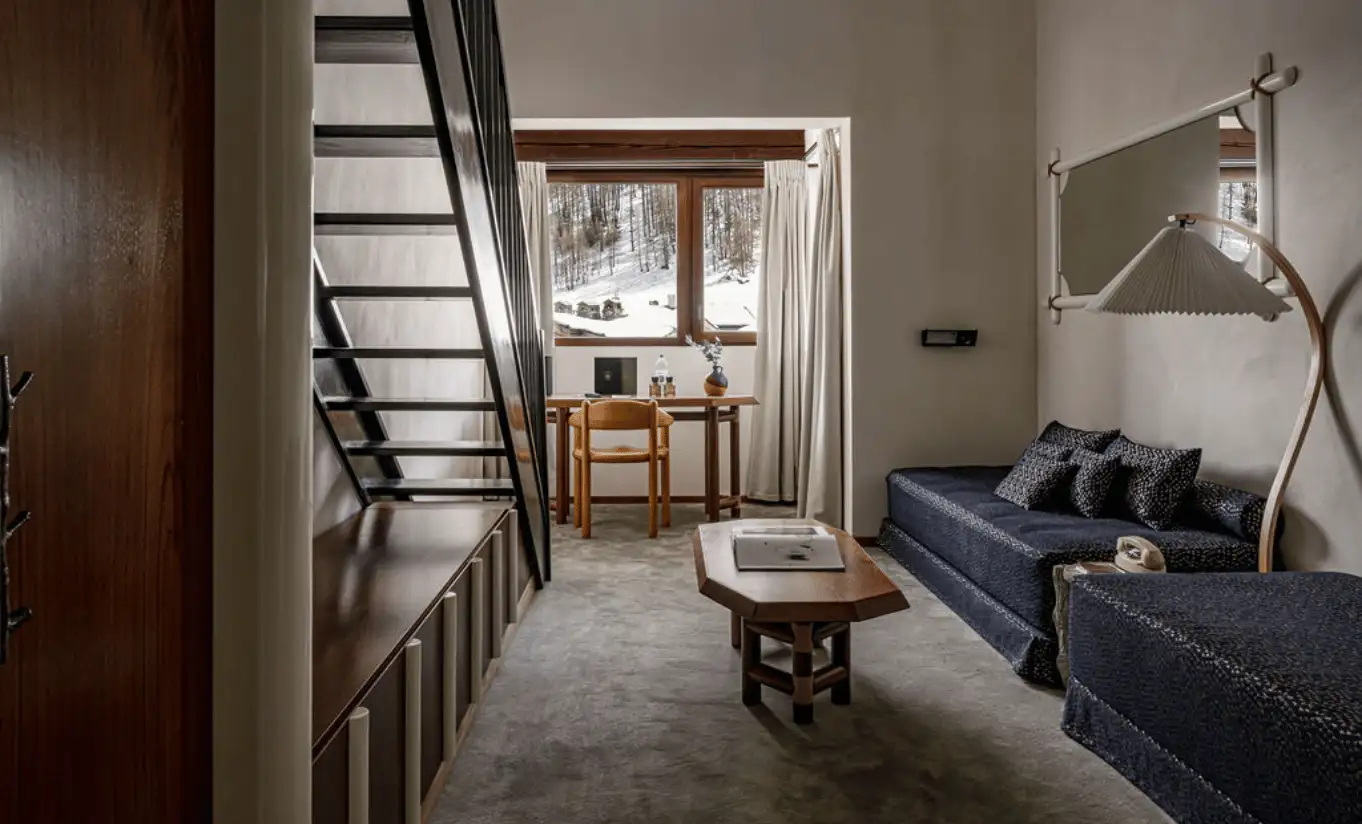 Mezzanine living area with a wooden staircase, a navy blue sofa and a reading lamp in the Loft at Experimental Chalet Val d'Isère