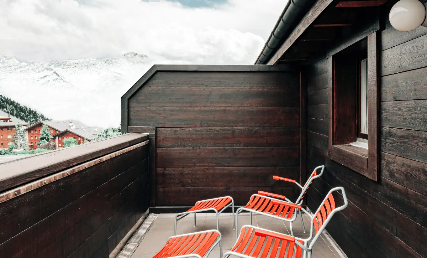 Private terrace with red chairs and a view of the alpine village in the Junior Suite Terrace at Experimental Chalet Verbier
