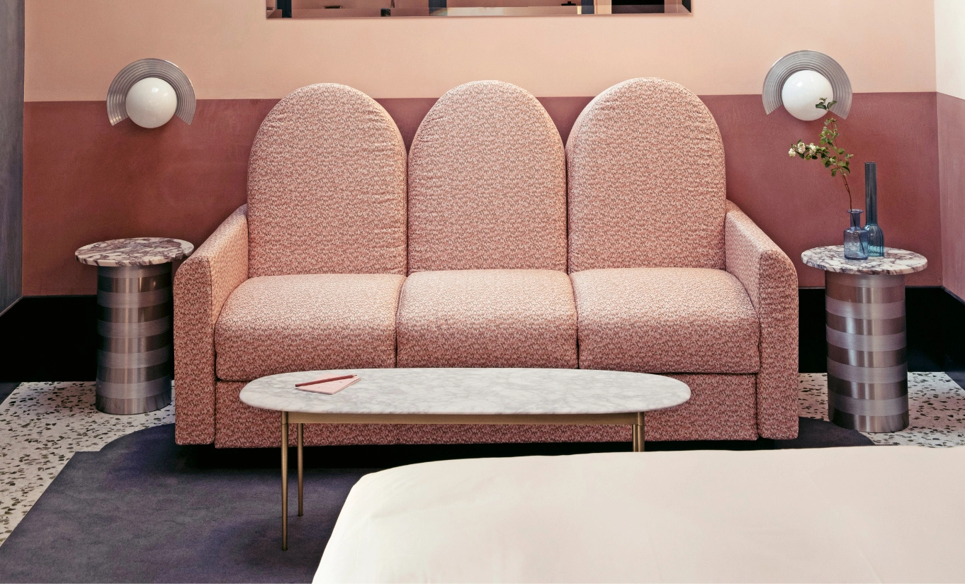 Il Palazzo Experimental pink boucle curved sofa with slim chrome side tables in a blush suite in Venice