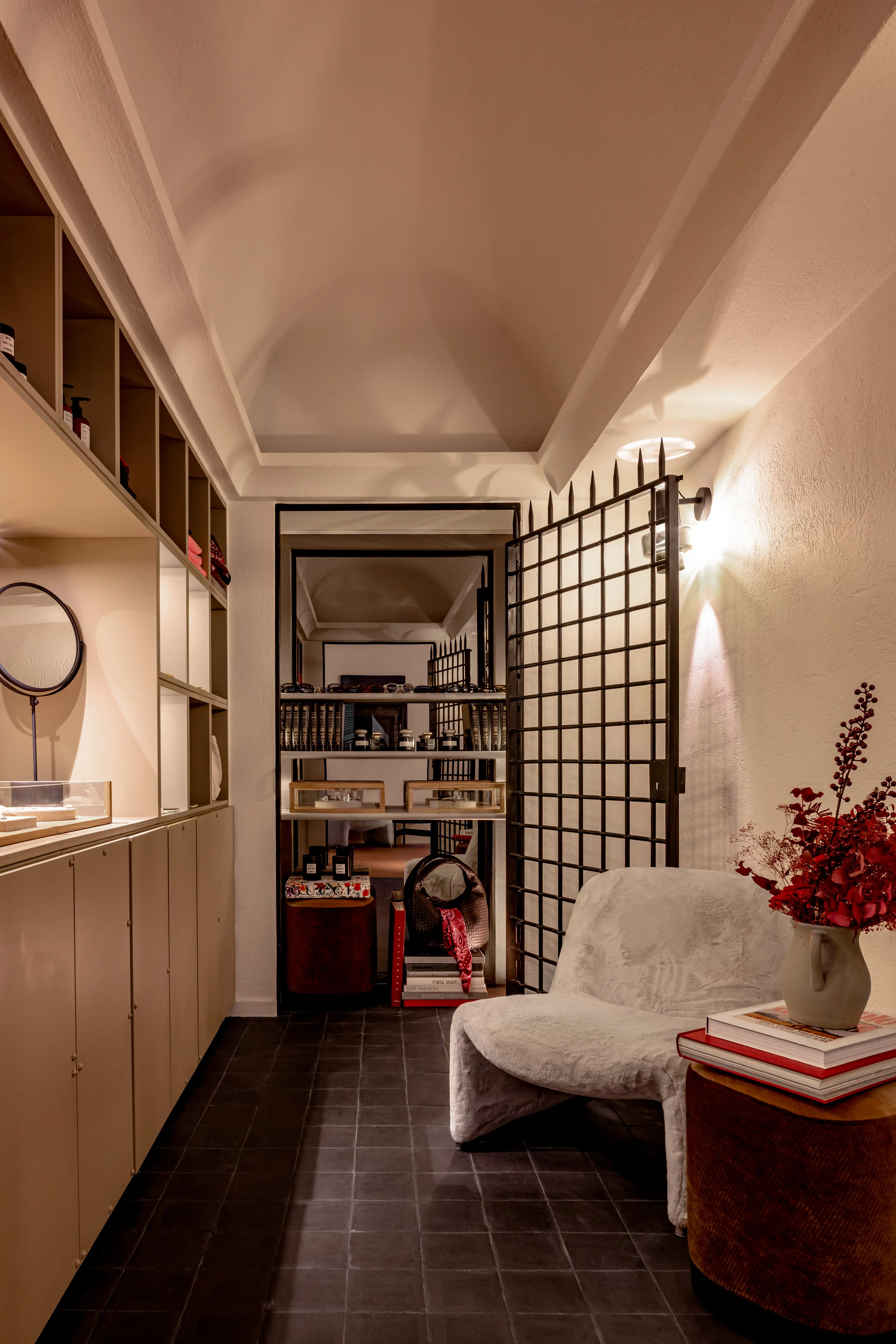Boutique with warm lighting, wooden shelving, a fluffy armchair and a bouquet of red flowers at Experimental Marais, luxury boutique hotel in le Marais, Paris