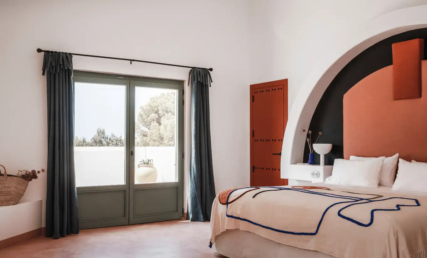 Bright bedroom with terracotta arch headboard, white bedding and garden view window – Menorca Experimental hotel, Experimental Group.