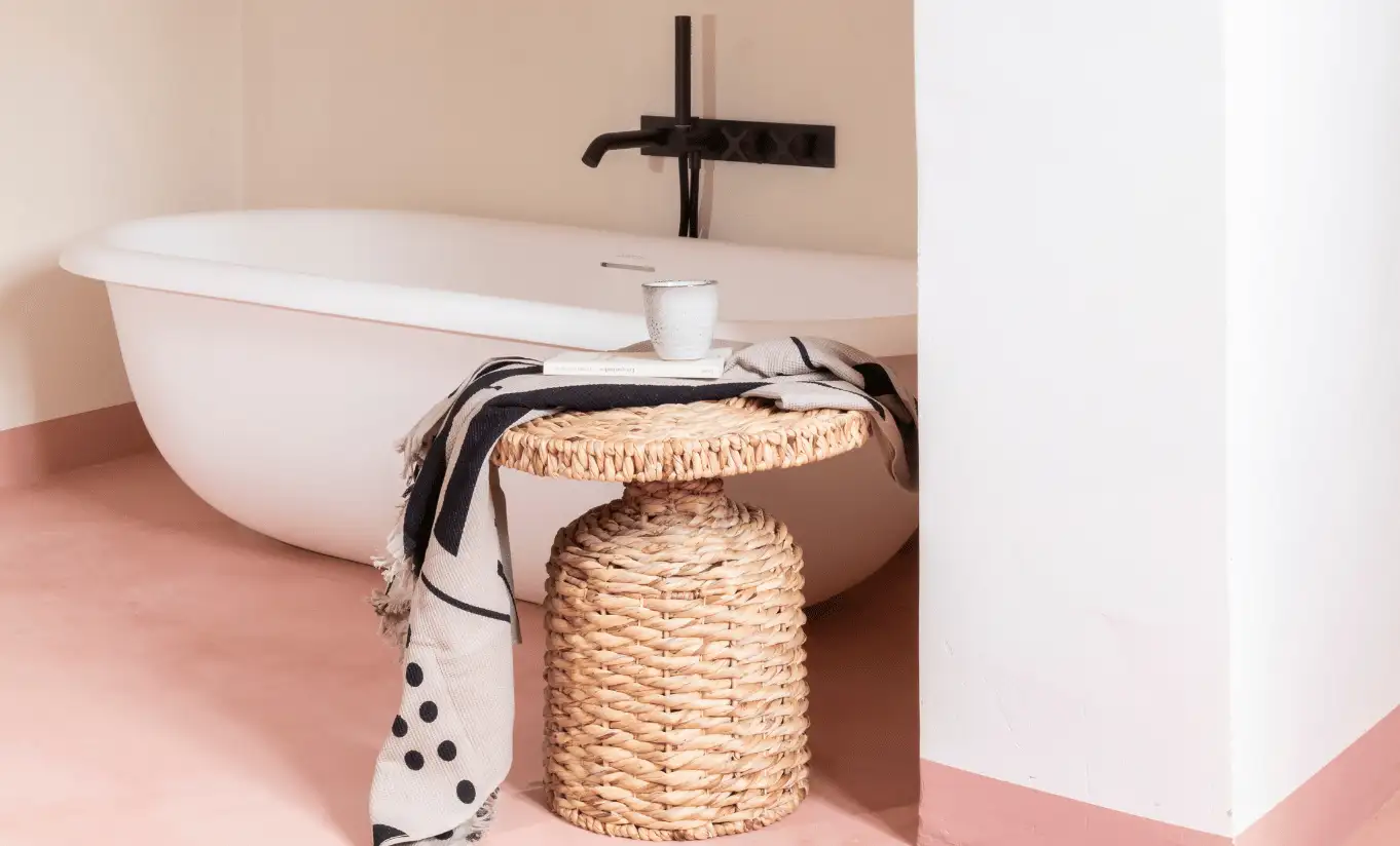 Minimalist bathroom with freestanding white bathtub, pink floor tiles and wicker basket – Menorca Experimental hotel, Experimental Group.