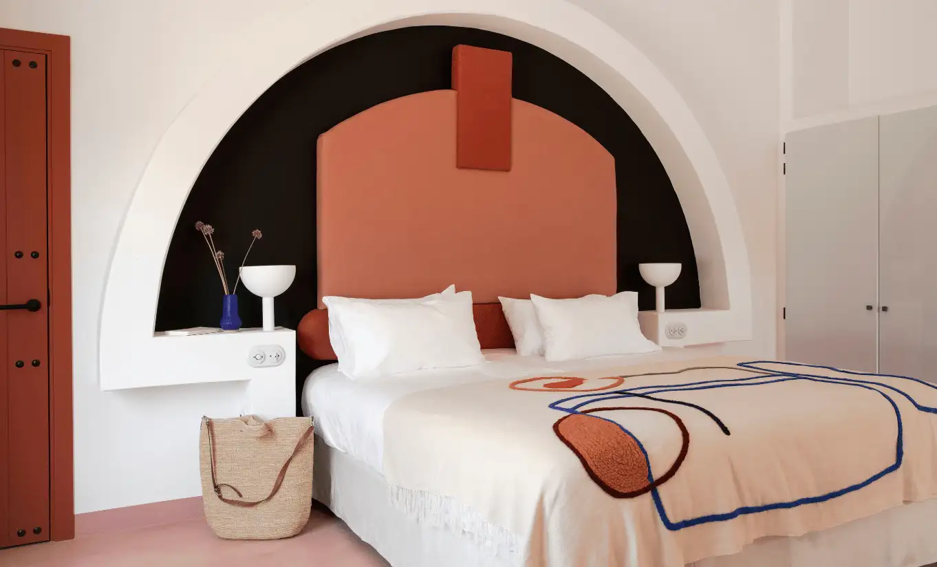 Double bedroom with bold terracotta curved arch alcove and warm neutral tones – Menorca Experimental hotel, Experimental Group.