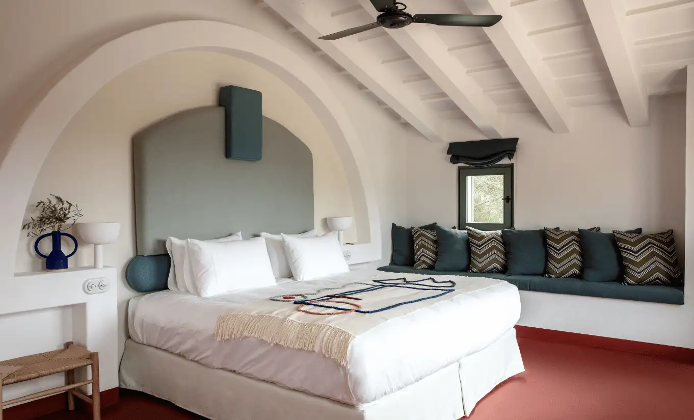 Menorca Experimental by Experimental Group – elegant vaulted bedroom with arched white ceiling, sage green bedding and handcrafted kilim cushions