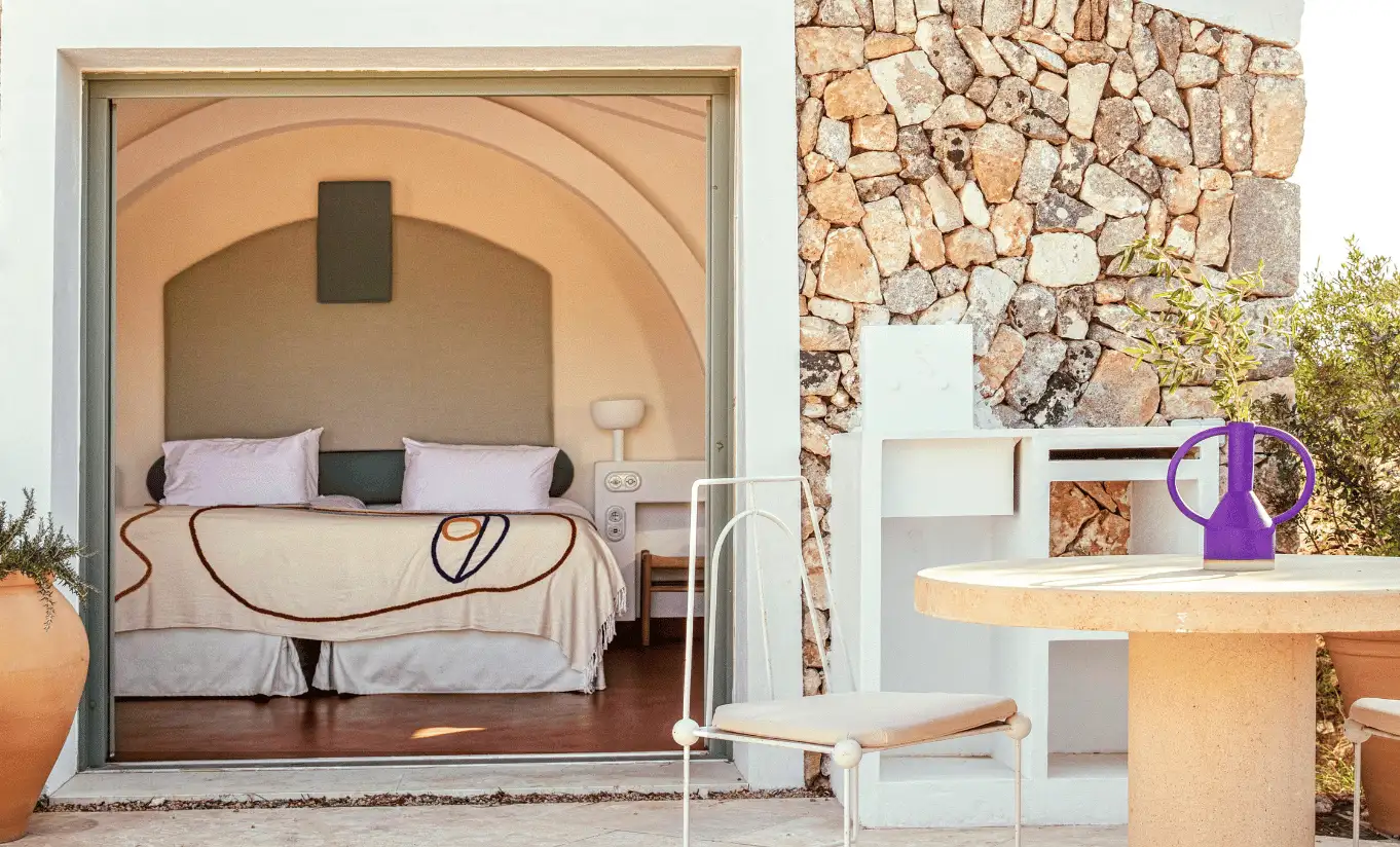 Menorca Experimental by Experimental Group – intimate bedroom alcove with arched stone surround, wooden writing desk and dried wildflower arrangement