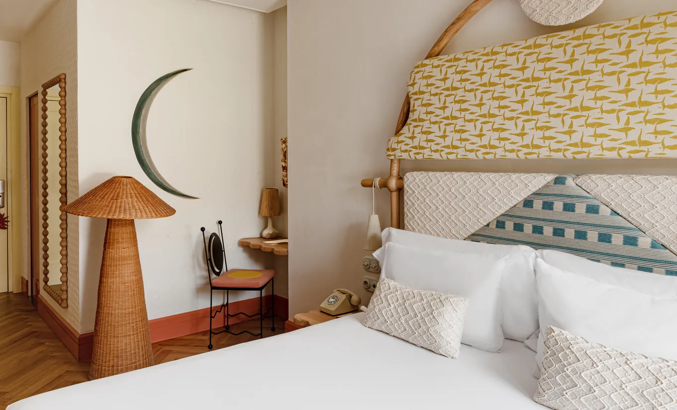 Cozy attic-style bedroom with sloped ceiling, botanical wallpaper, white bedding and vintage wooden desk at Montesol Experimental hotel, Experimental Group.