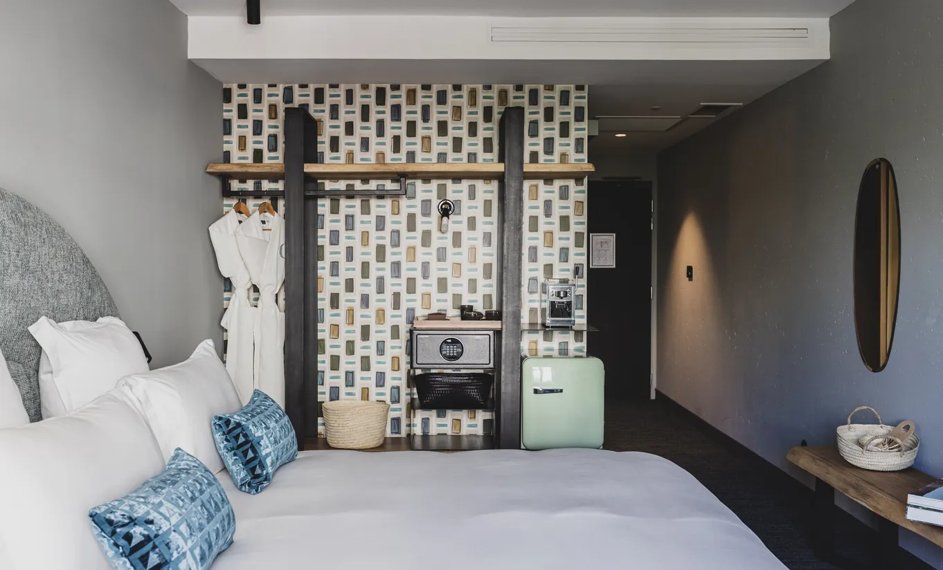 Le Garage Biarritz Experimental hotel room with grey upholstered headboard, blue patterned cushions, and decorative lattice partition screen