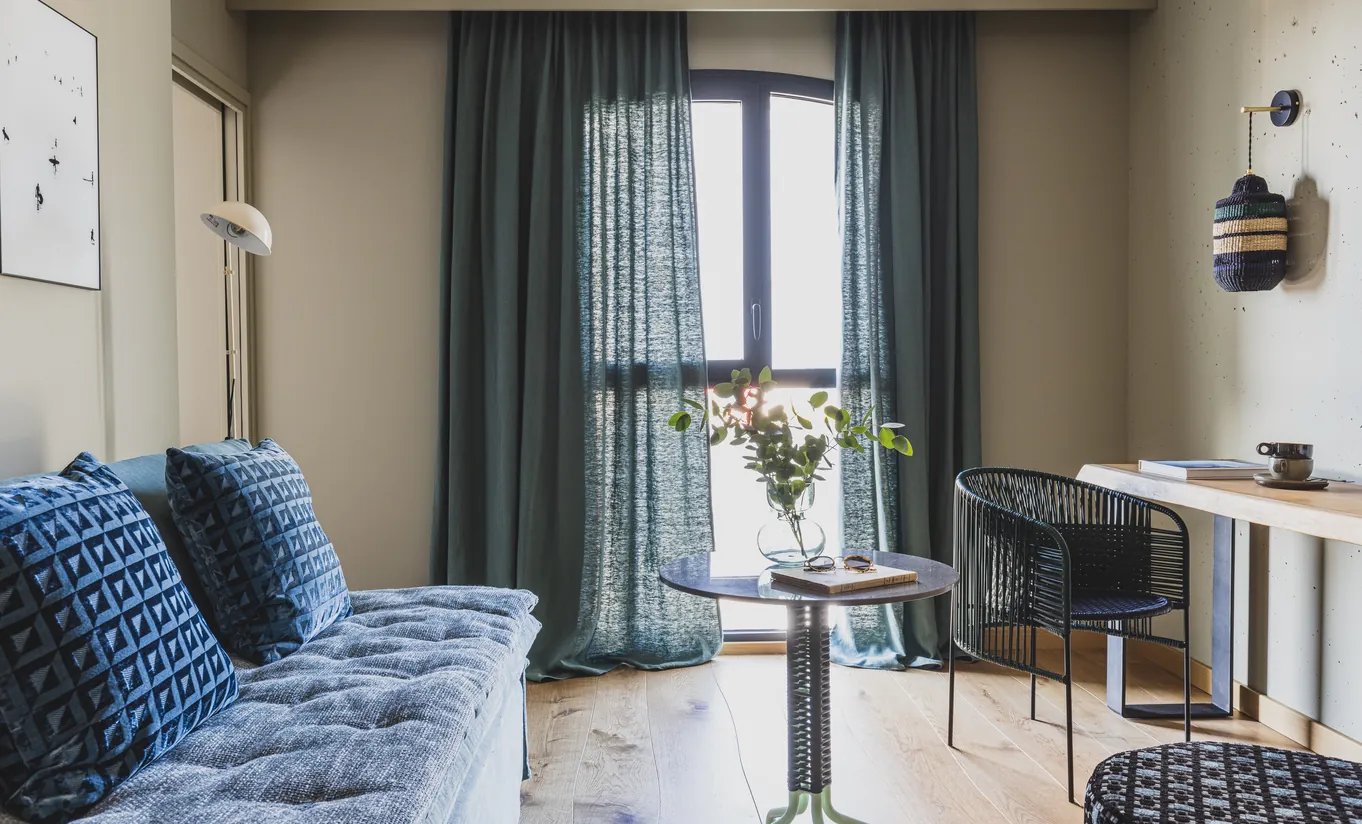 Experimental Group hotel modern living room with blue sofa and floor-to-ceiling curtains
