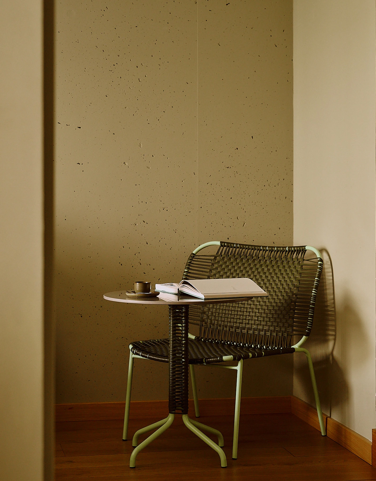 Intimate reading corner with a woven chair and a small table, reflecting the soothing atmosphere of Experimental Group establishments.