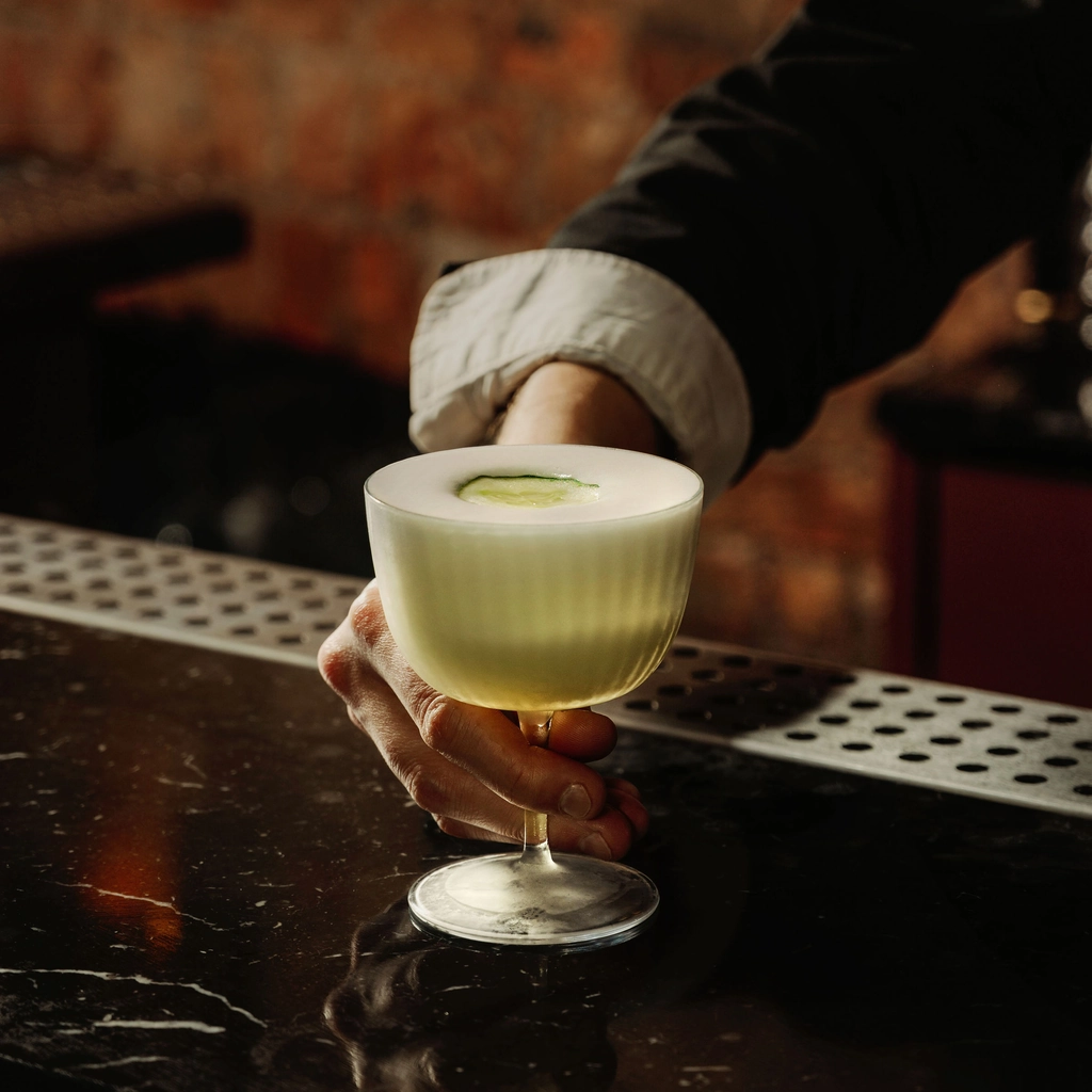 A handcrafted signature cocktail being served at an Experimental Group bar counter.