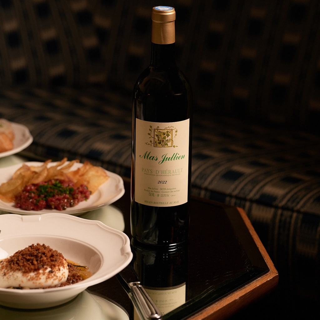 Uma garrafa de vinho fino harmonizada com pratos gourmet numa mesa de um restaurante do Experimental Group.