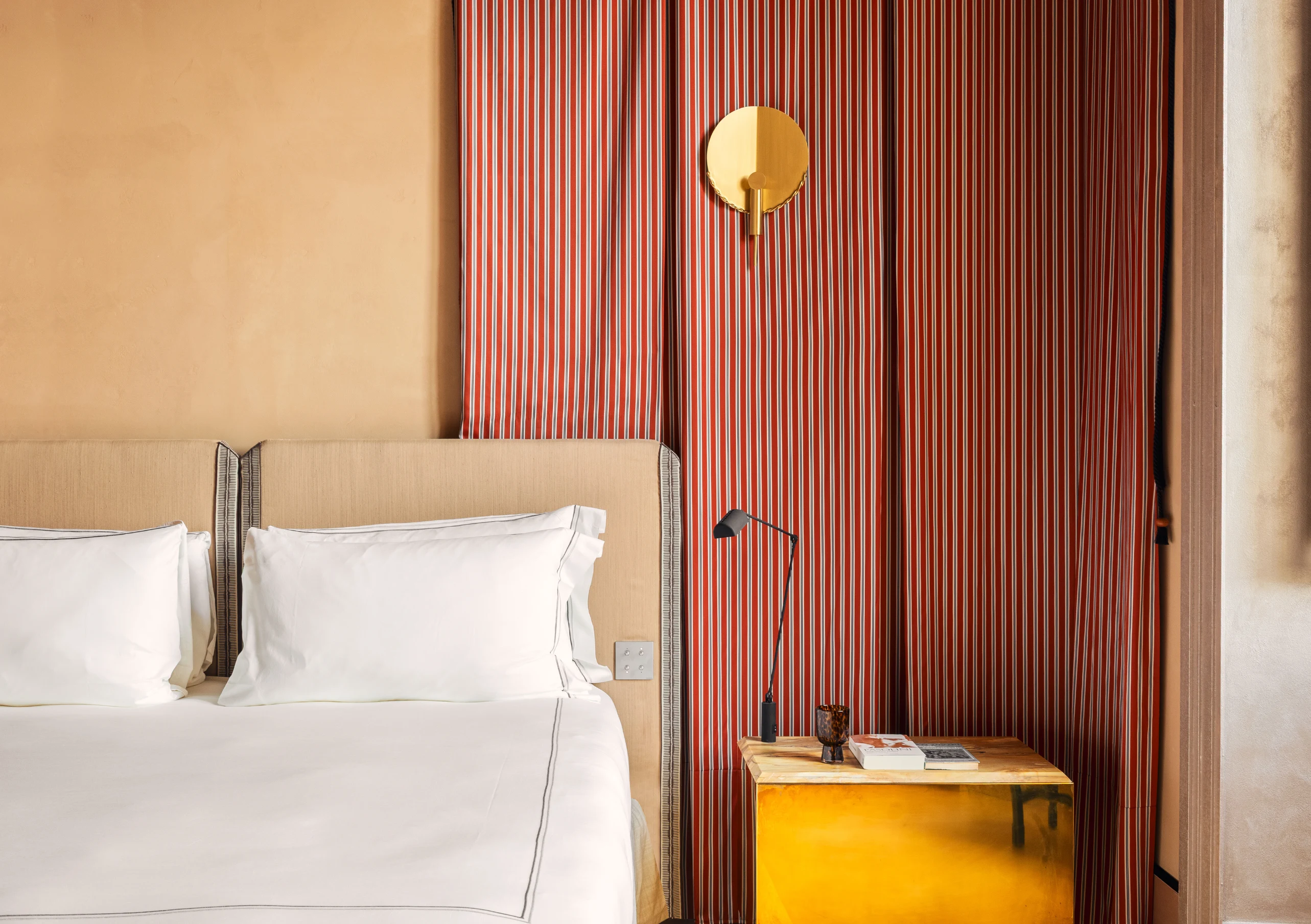 Hotel bedroom with white bedding, mustard yellow nightstand and sculptural globe wall sconce at Experimental Roma, Experimental Group.