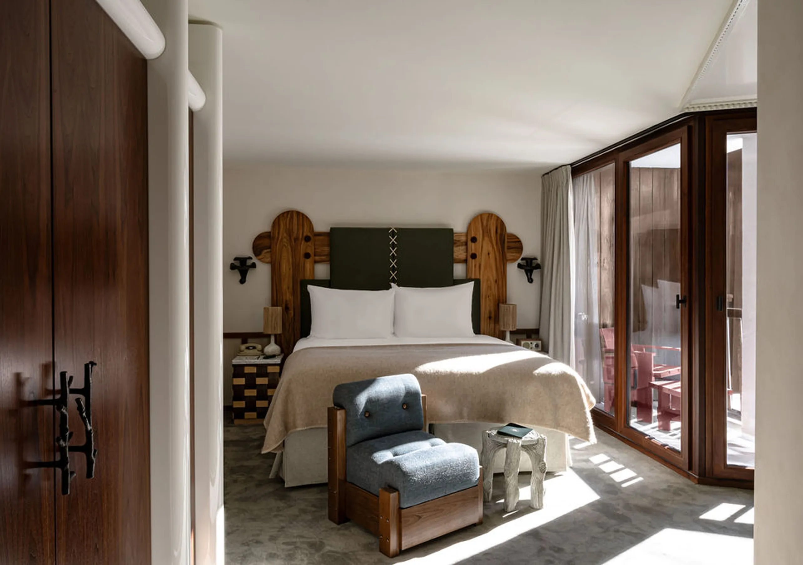 Bright bedroom with a white double bed, wooden wardrobe and large windows in the Junior Suite Solaise at Experimental Chalet Val d'Isère