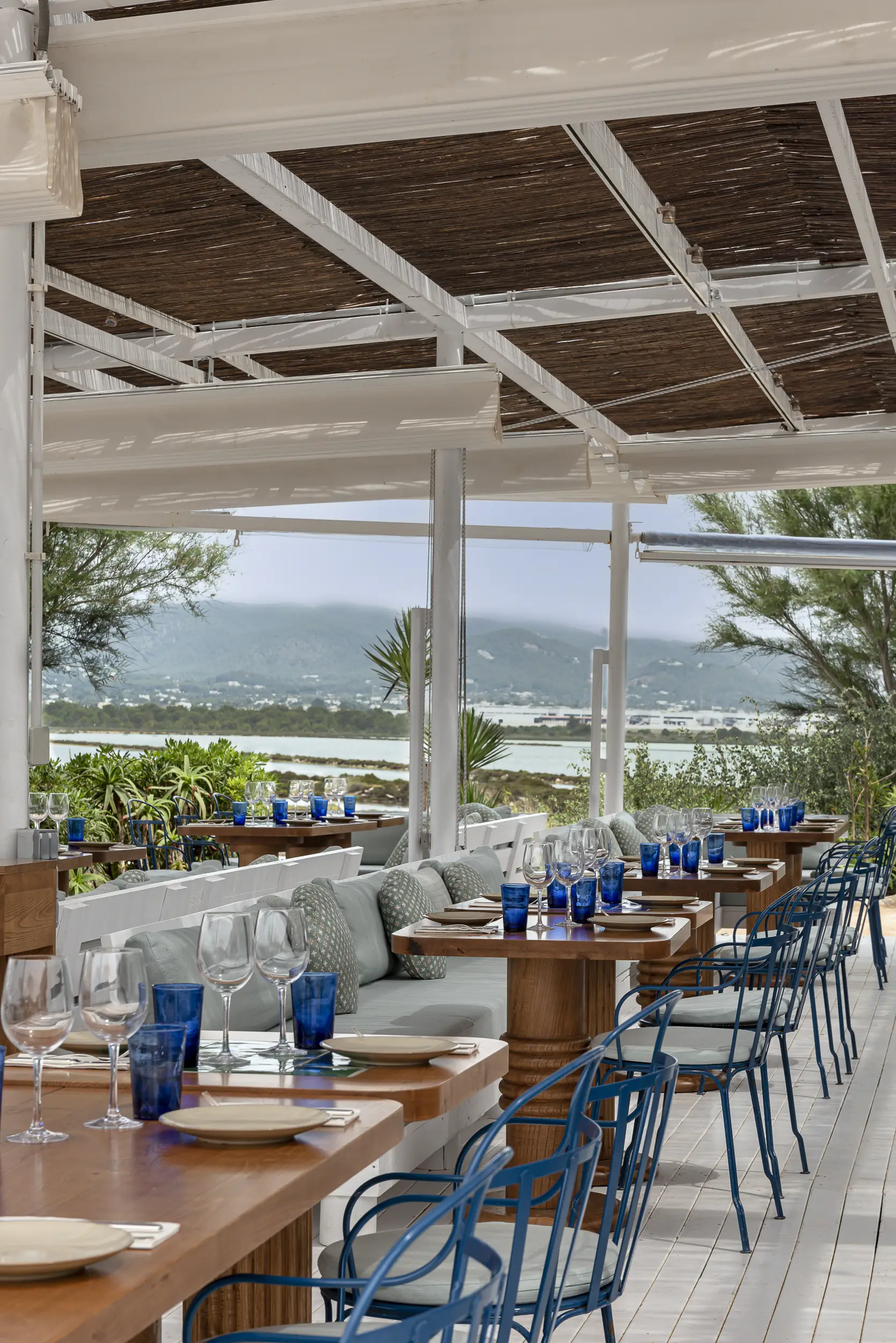 Bancone ovale in legno intagliato sotto un rigoglioso arco floreale pensile su pavimento in mattoni a spina di pesce nel ristorante dell'Experimental Beach Ibiza.
