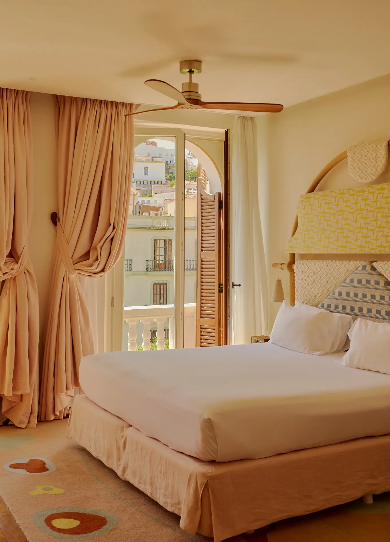 Chambre élégante et lumineuse à l'Experimental Beach Ibiza, dotée d'un grand lit confortable, de rideaux beiges et d'une porte-fenêtre donnant sur l'extérieur.