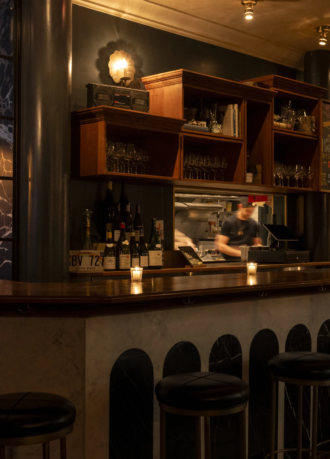 Balcão de bar elegante com prateleiras de madeira e iluminação suave no La Compagnie Wine Bar.