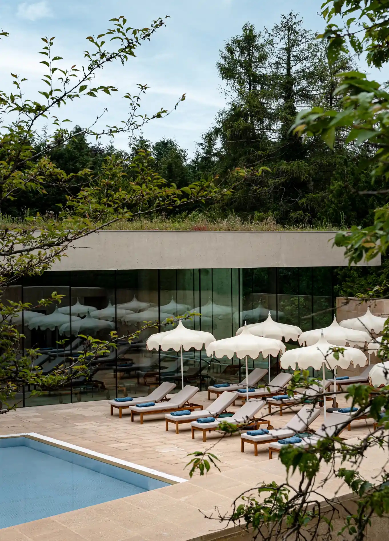 Piscina exterior com espreguiçadeiras e chapéus de sol no Cowley Manor Spa Hotel, Cotswolds