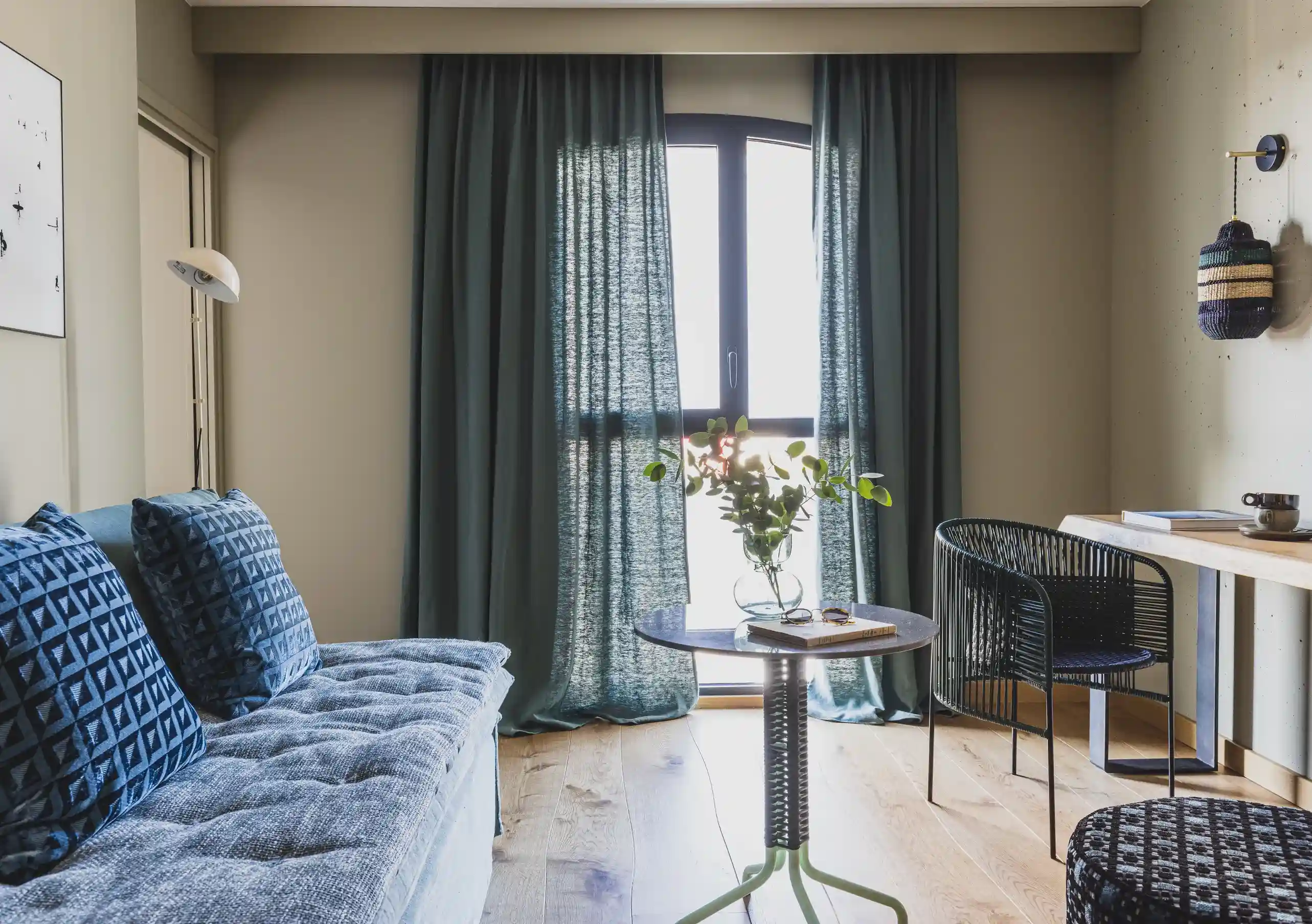 Experimental Group hotel modern living room with blue sofa and floor-to-ceiling curtains.